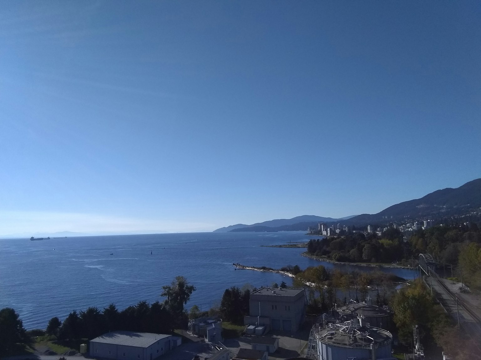 Vista panoramica dell'oceano blu e del cielo sereno con navi nel porto e montagne in lontananza