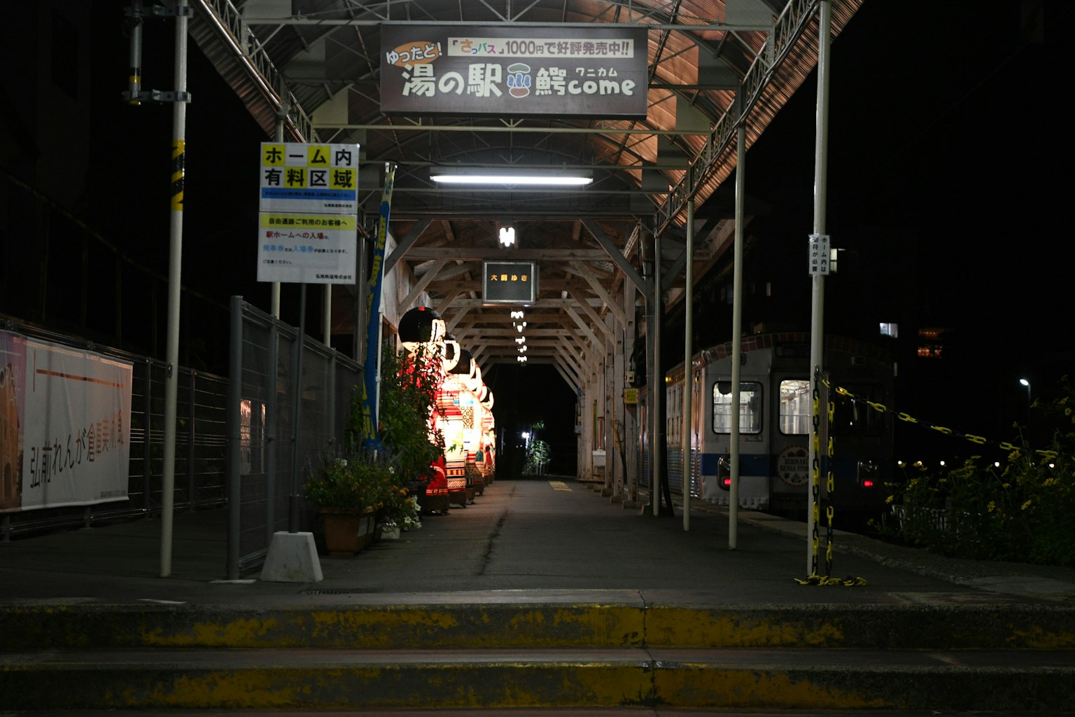 Illuminated station walkway at night with plants