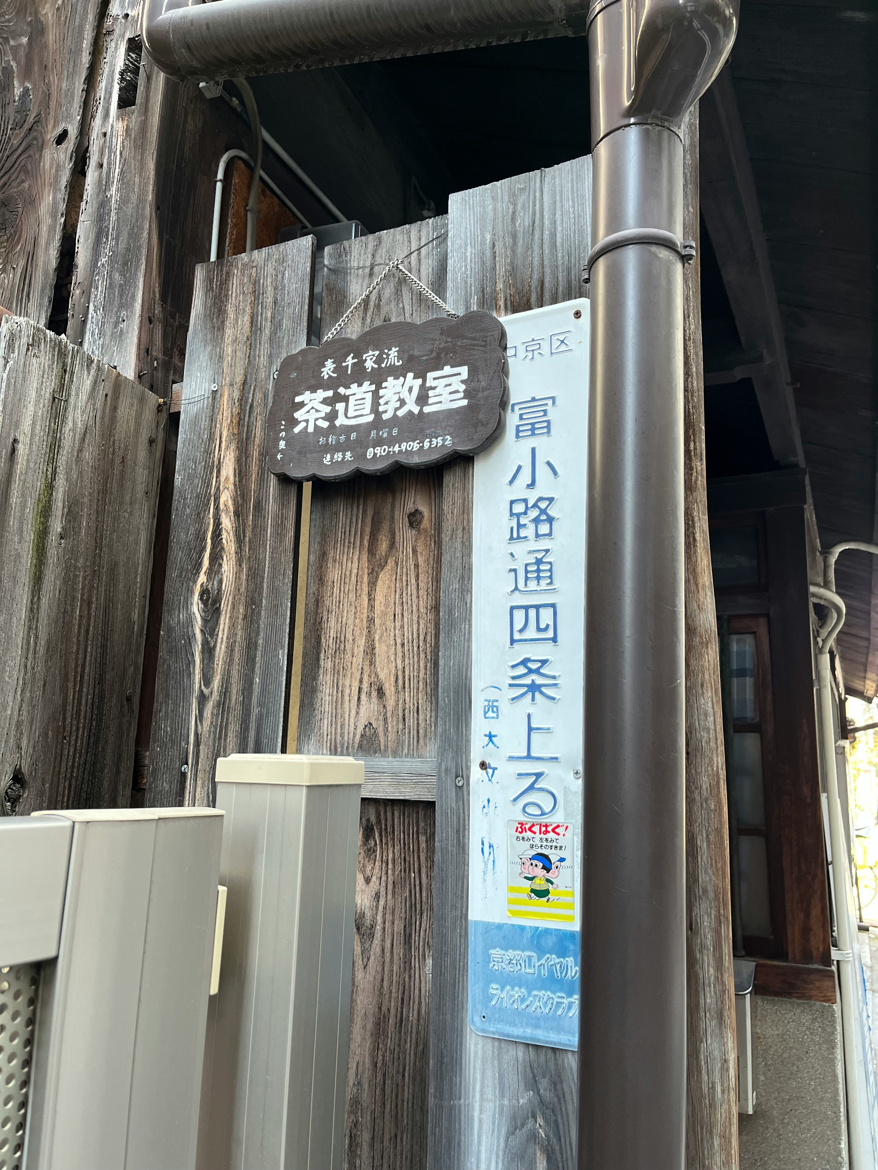 木製の看板と案内ポスターが掛かった路地の入口