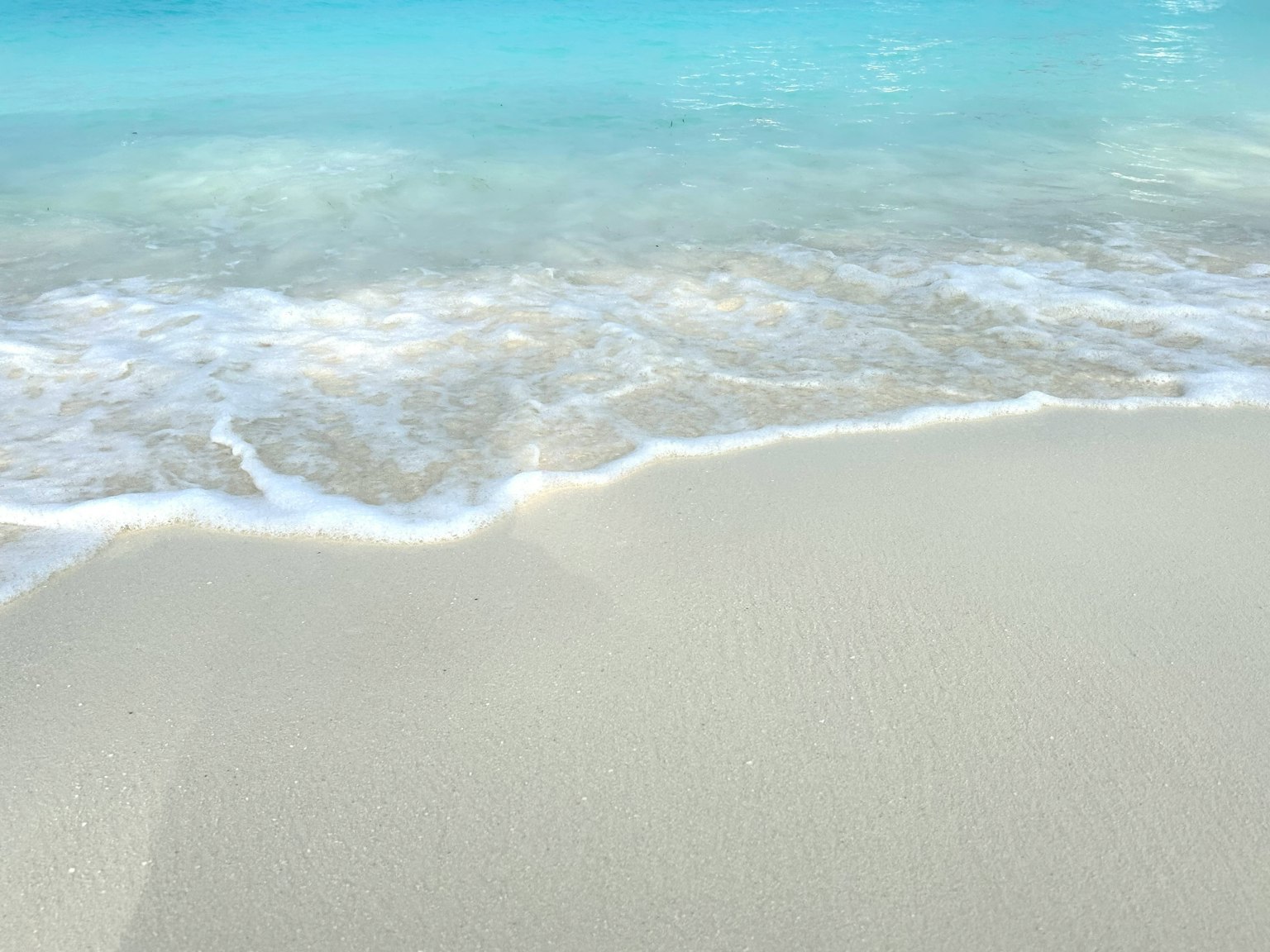 White sandy beach with gentle waves and clear blue water