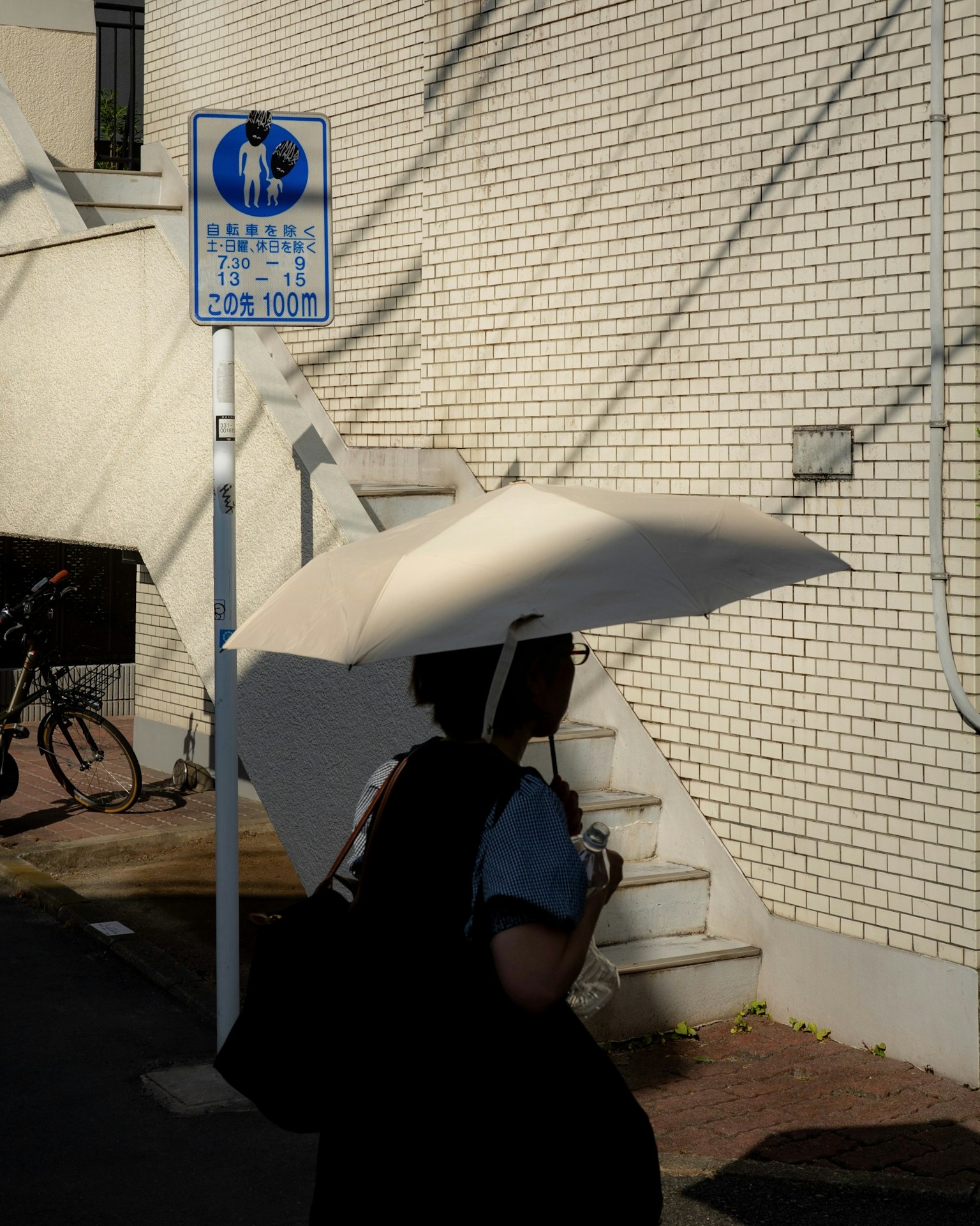 Eine Person, die mit einem weißen Regenschirm an einer Straßenecke geht