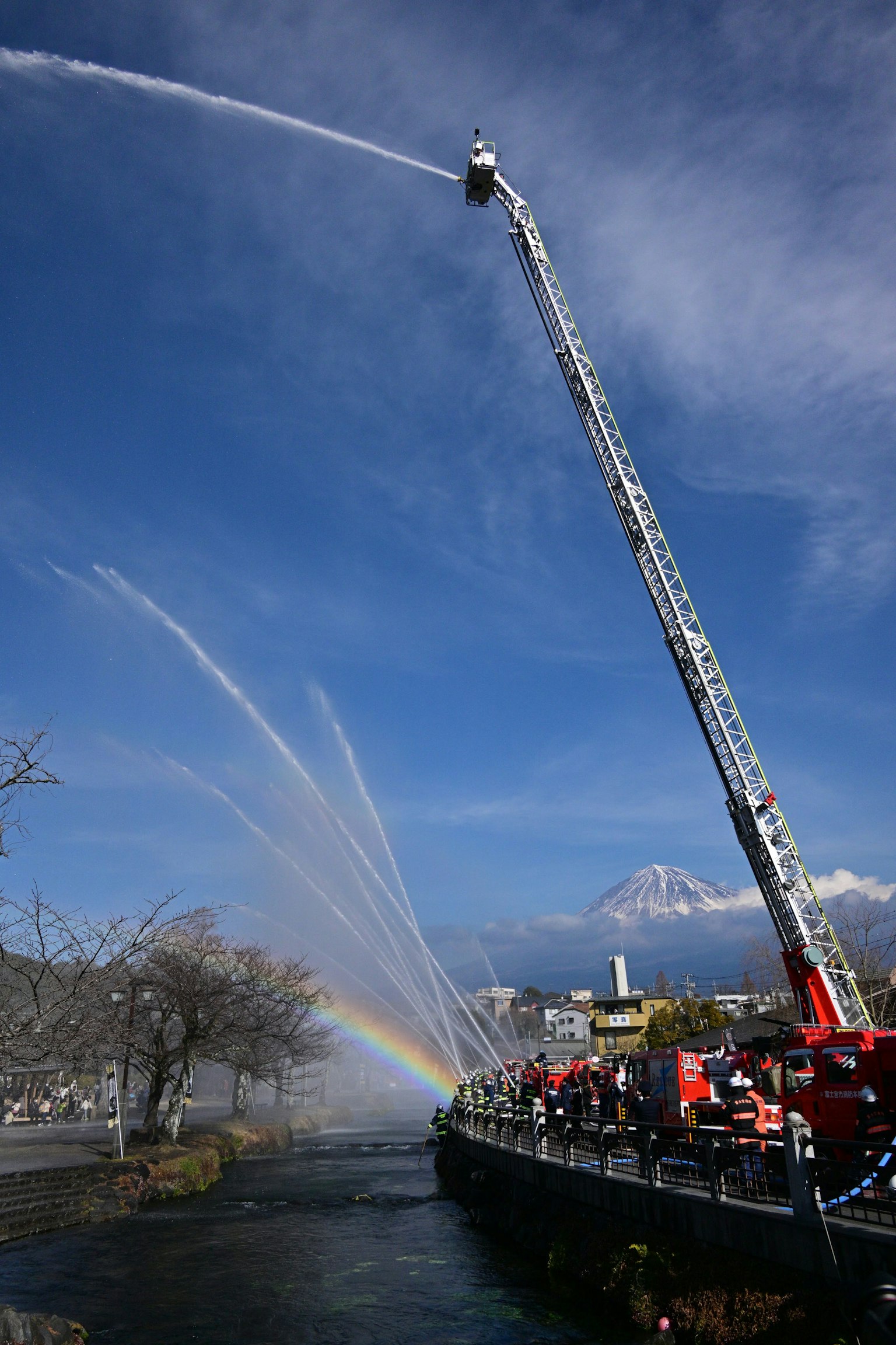 Échelle de camion de pompier pulvérisant de l'eau avec un arc-en-ciel en arrière-plan