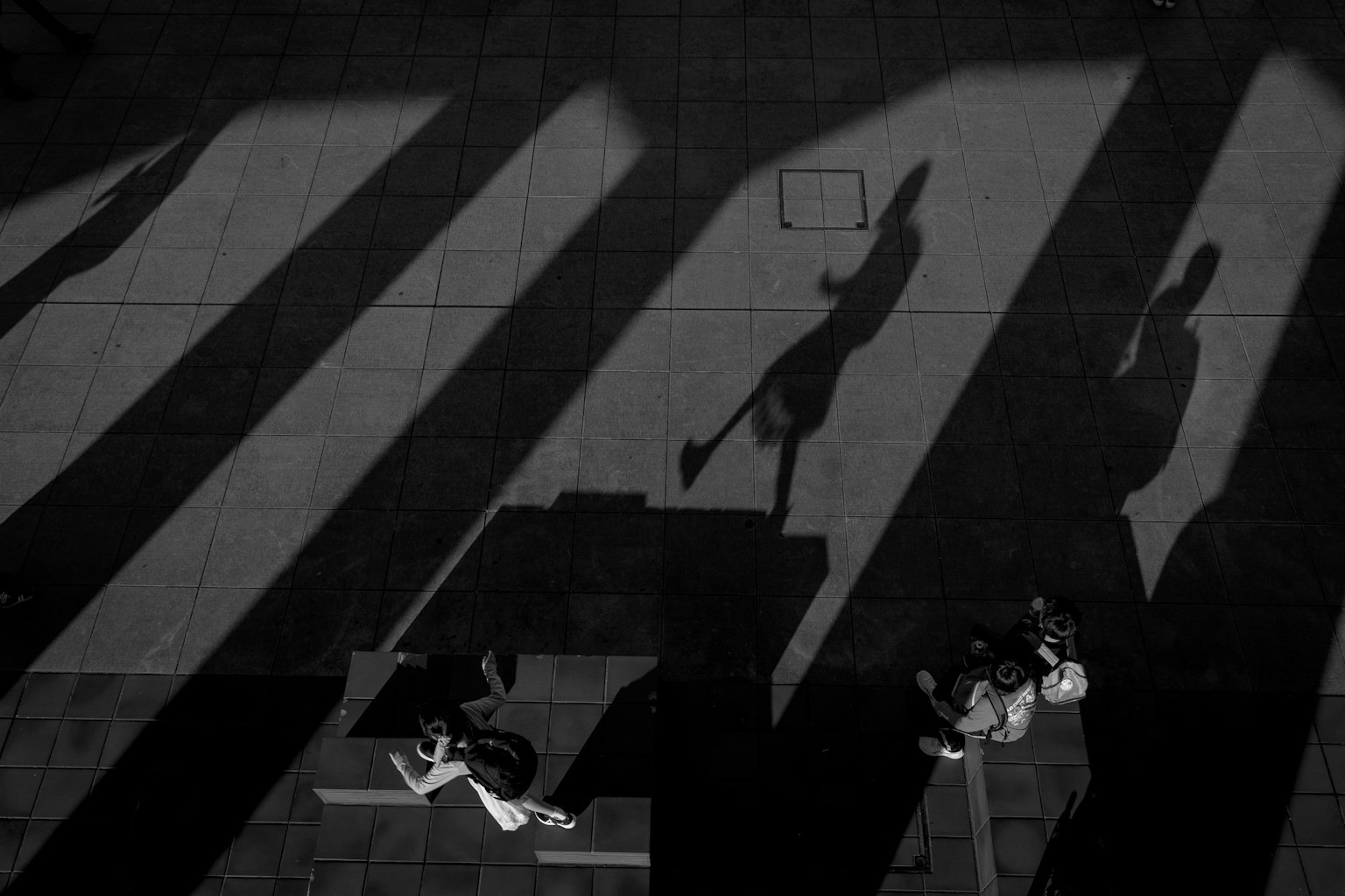 Black and white shadows intersecting in an urban scene with people walking