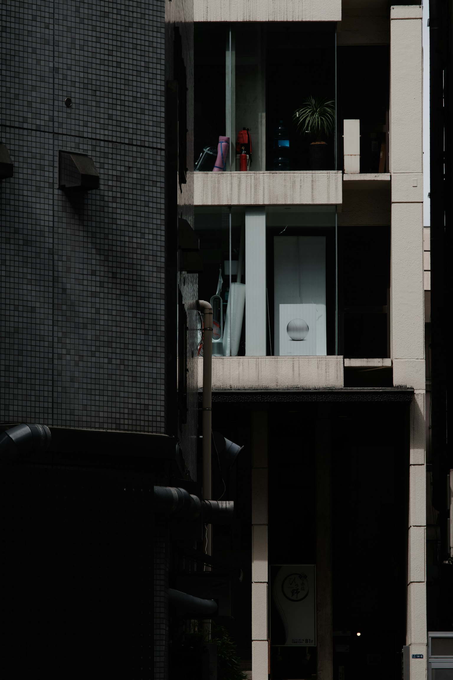 Balkon bangunan modern dengan orang dan tanaman menghadap jalan gelap