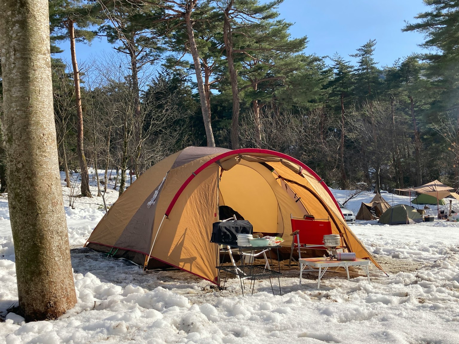 Brauner Zeltplatz in einem verschneiten Campingplatz mit roten Stühlen