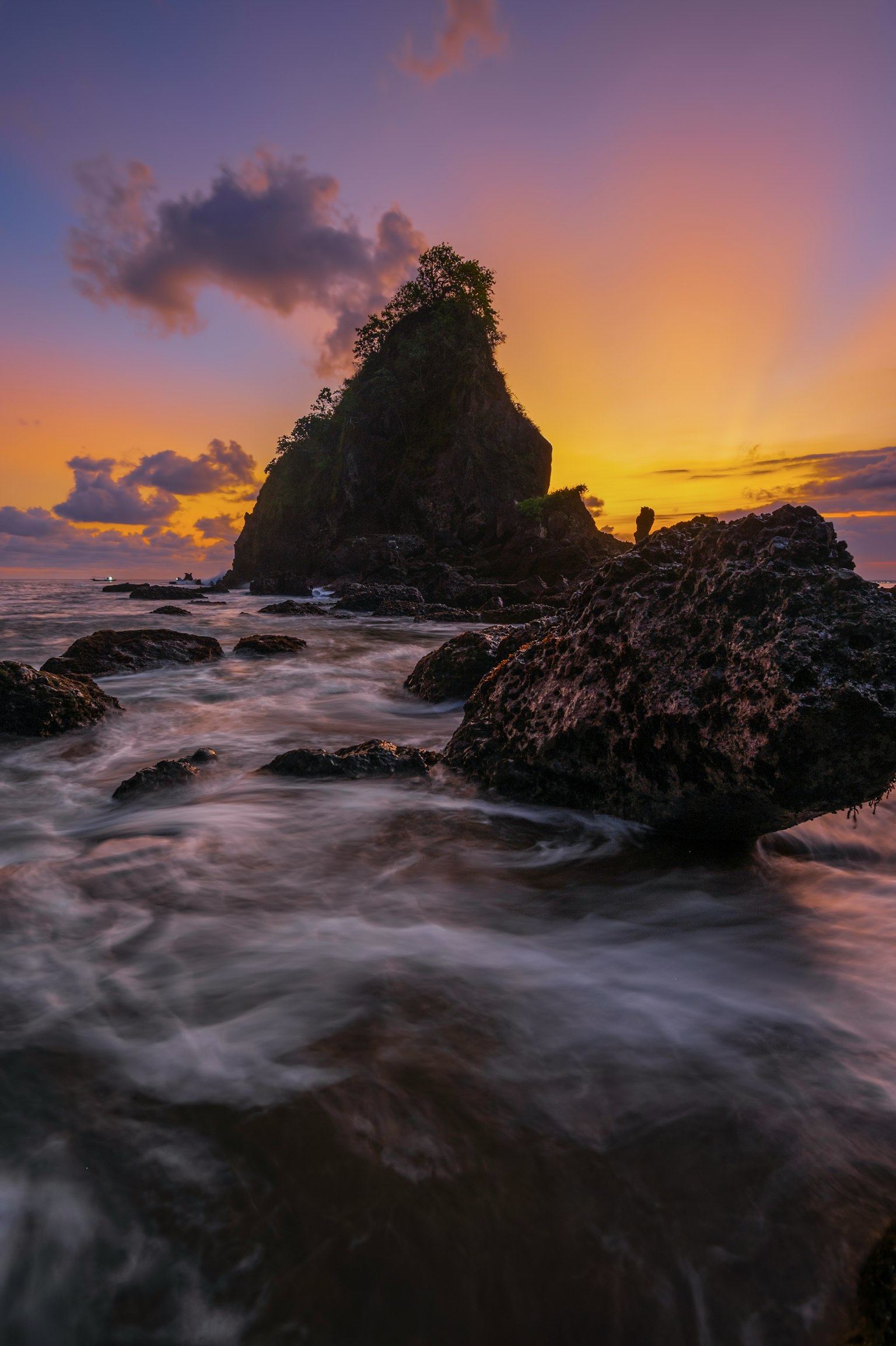 Formación rocosa costera con olas al atardecer