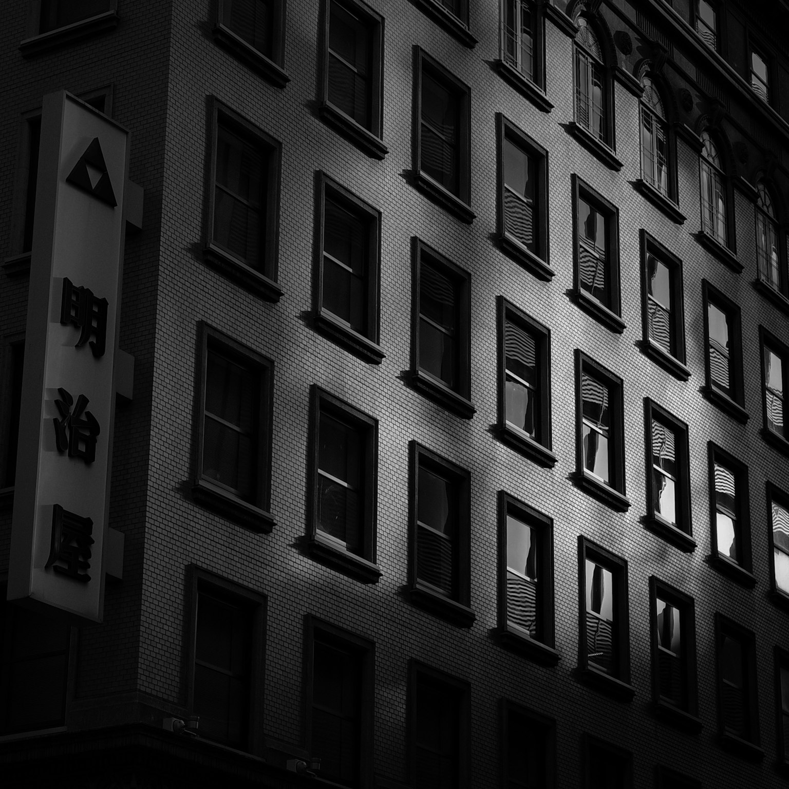 Schwarz-weiße Gebäudeansicht mit markanten Fensterreflexionen und Schatten