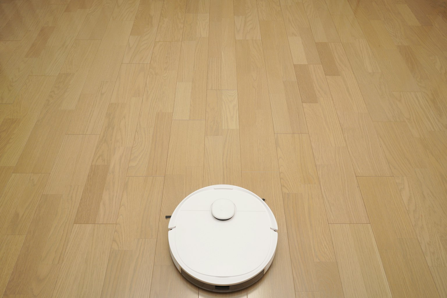 Aspirateur robot blanc sur un sol en bois