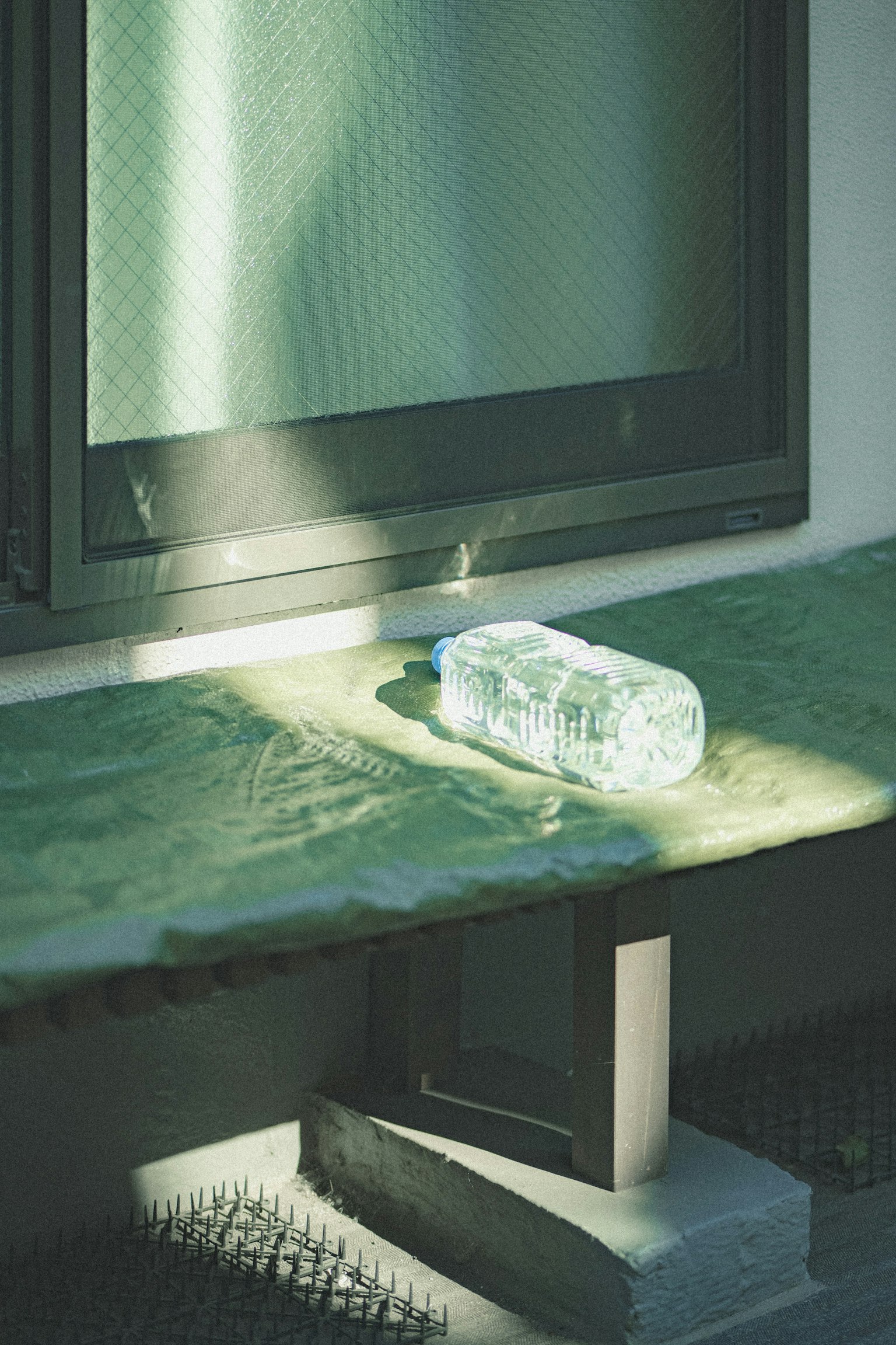 窓の近くに置かれた透明な水のボトルと柔らかな光