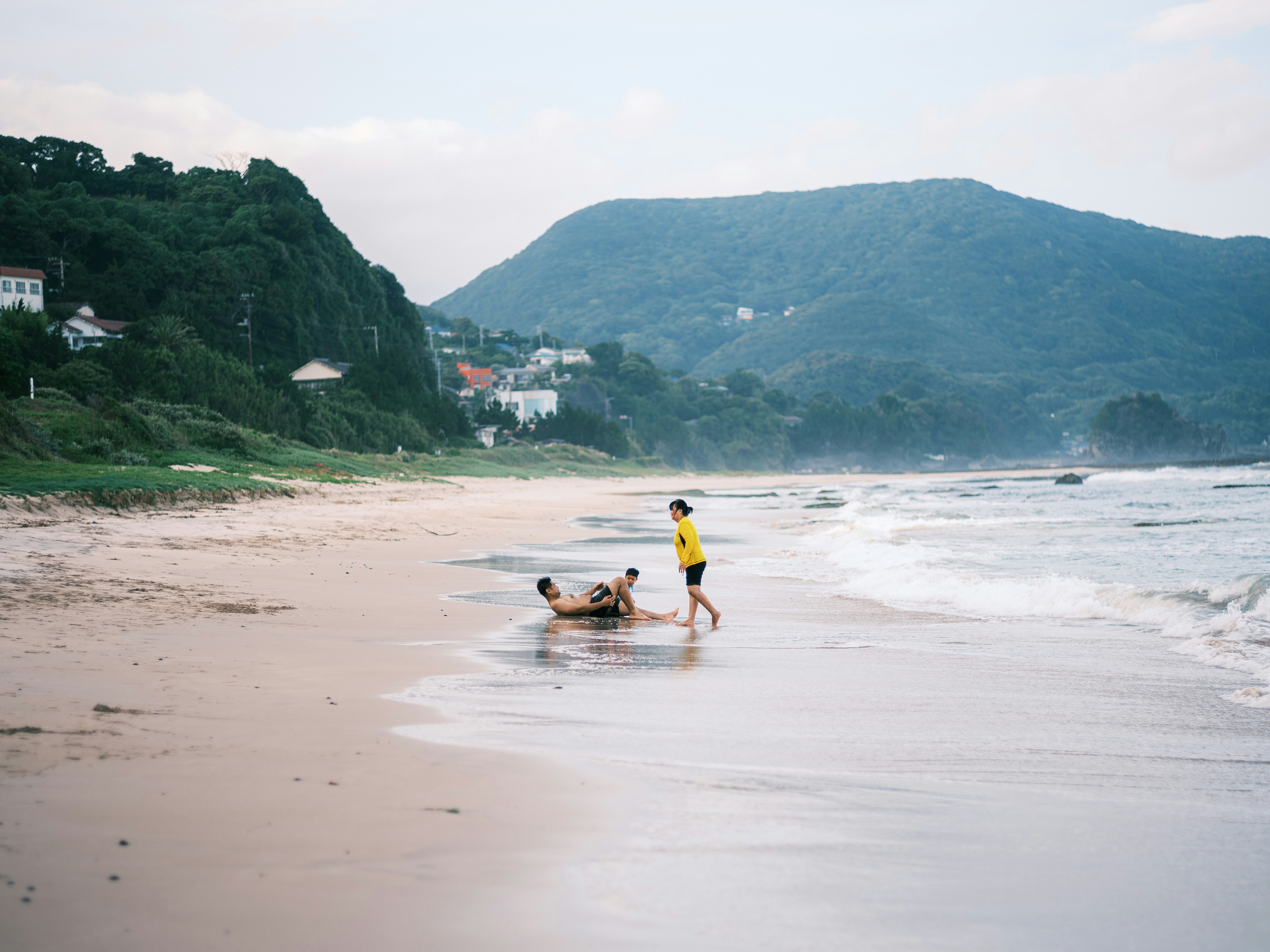 海辺で遊ぶ人と波のある砂浜の風景