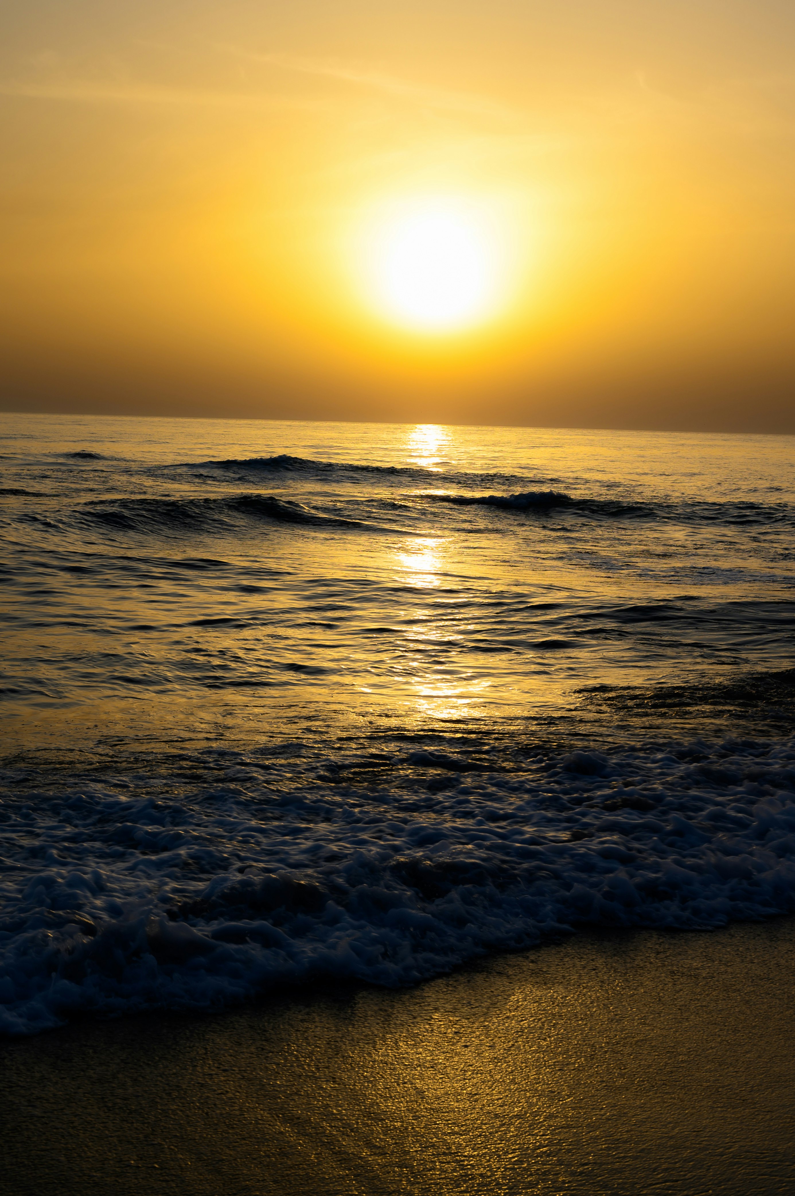 夕日に照らされた海と波のある砂浜