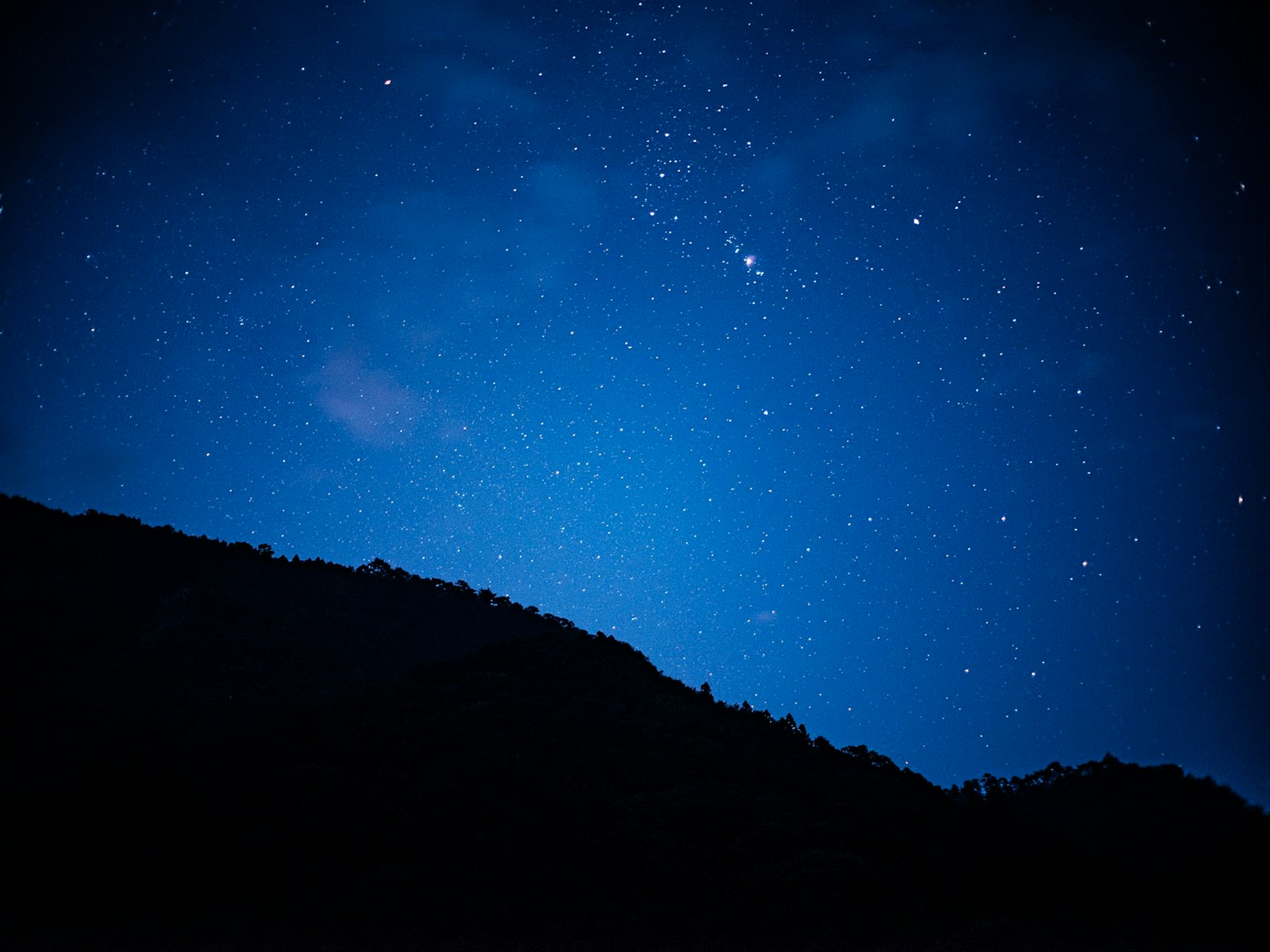 Cielo notturno pieno di stelle e silhouette di montagna