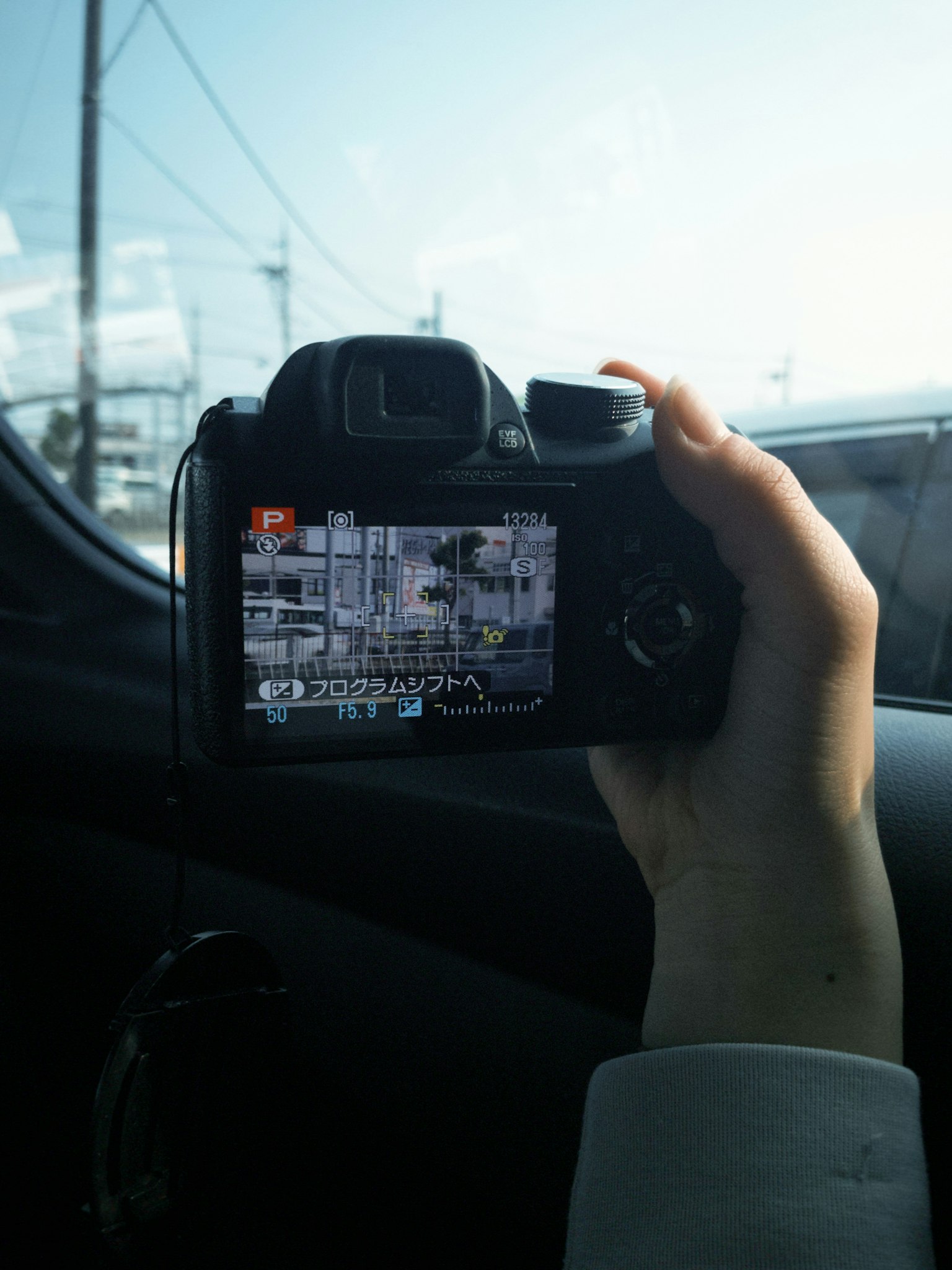 Hand hält eine Kamera mit einem Display, das eine aufgenommene Szene zeigt