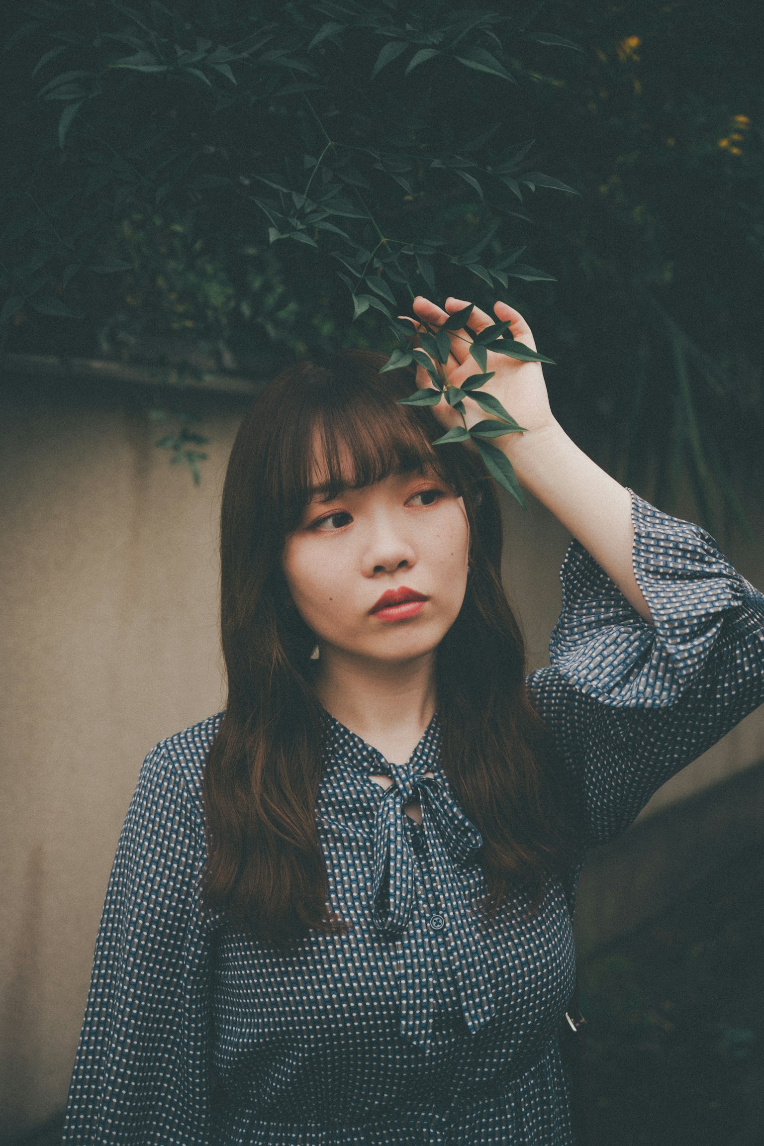 一位年輕女性在思考的姿勢中拿著綠葉