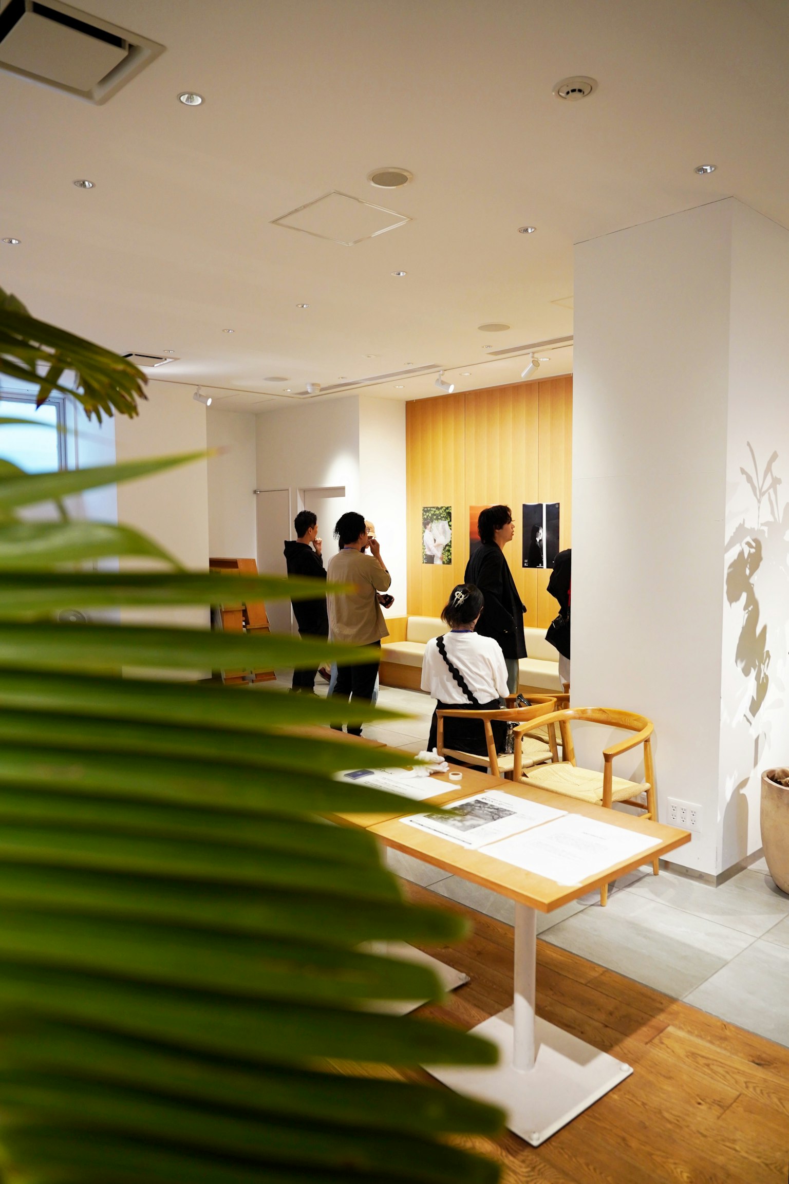 Mọi người tương tác trong một quán cà phê hiện đại với thiết kế nội thất sáng và cây xanh ở phía trước