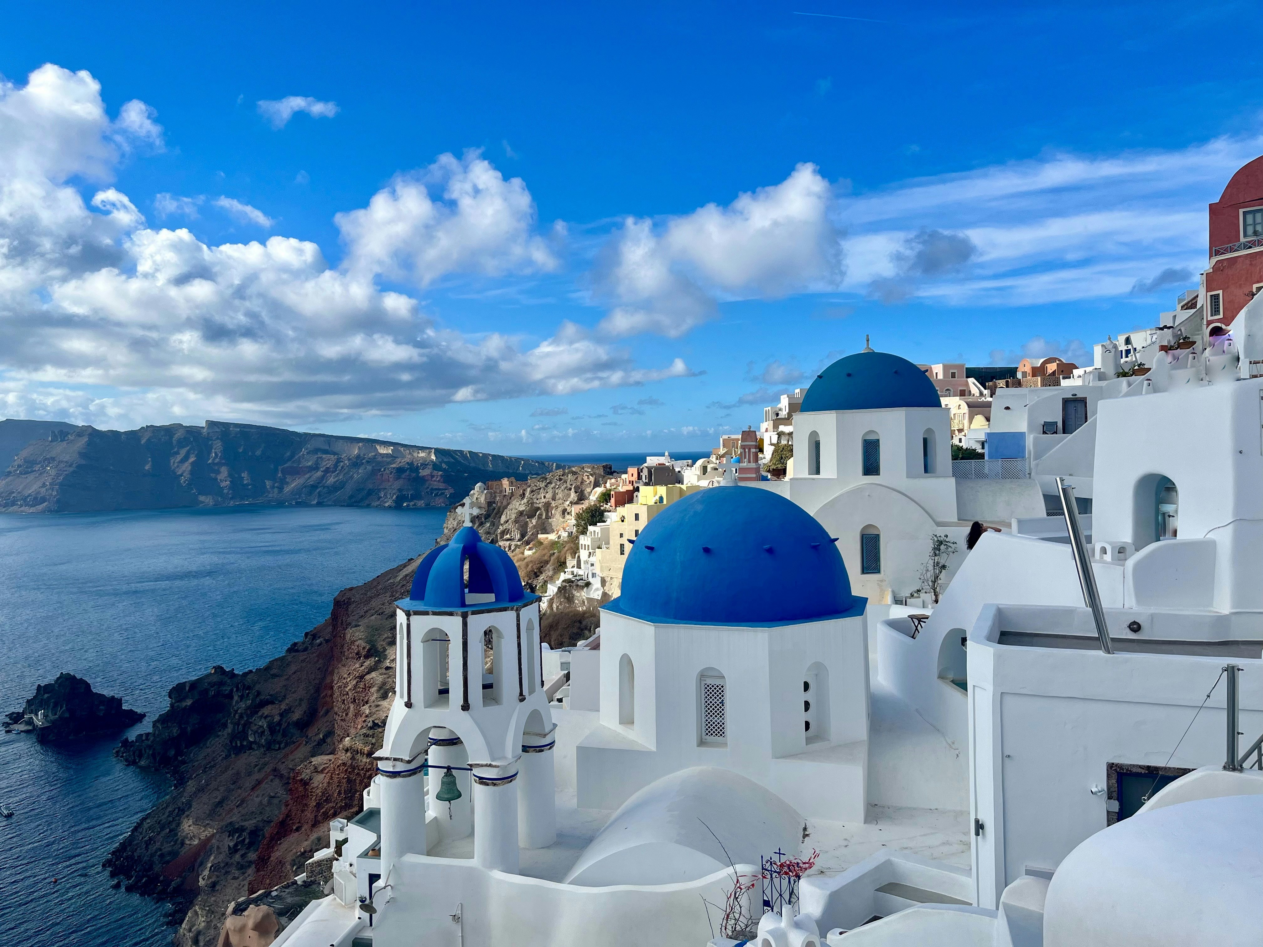 Cliffside view of white domed buildings overlooking the blue sea