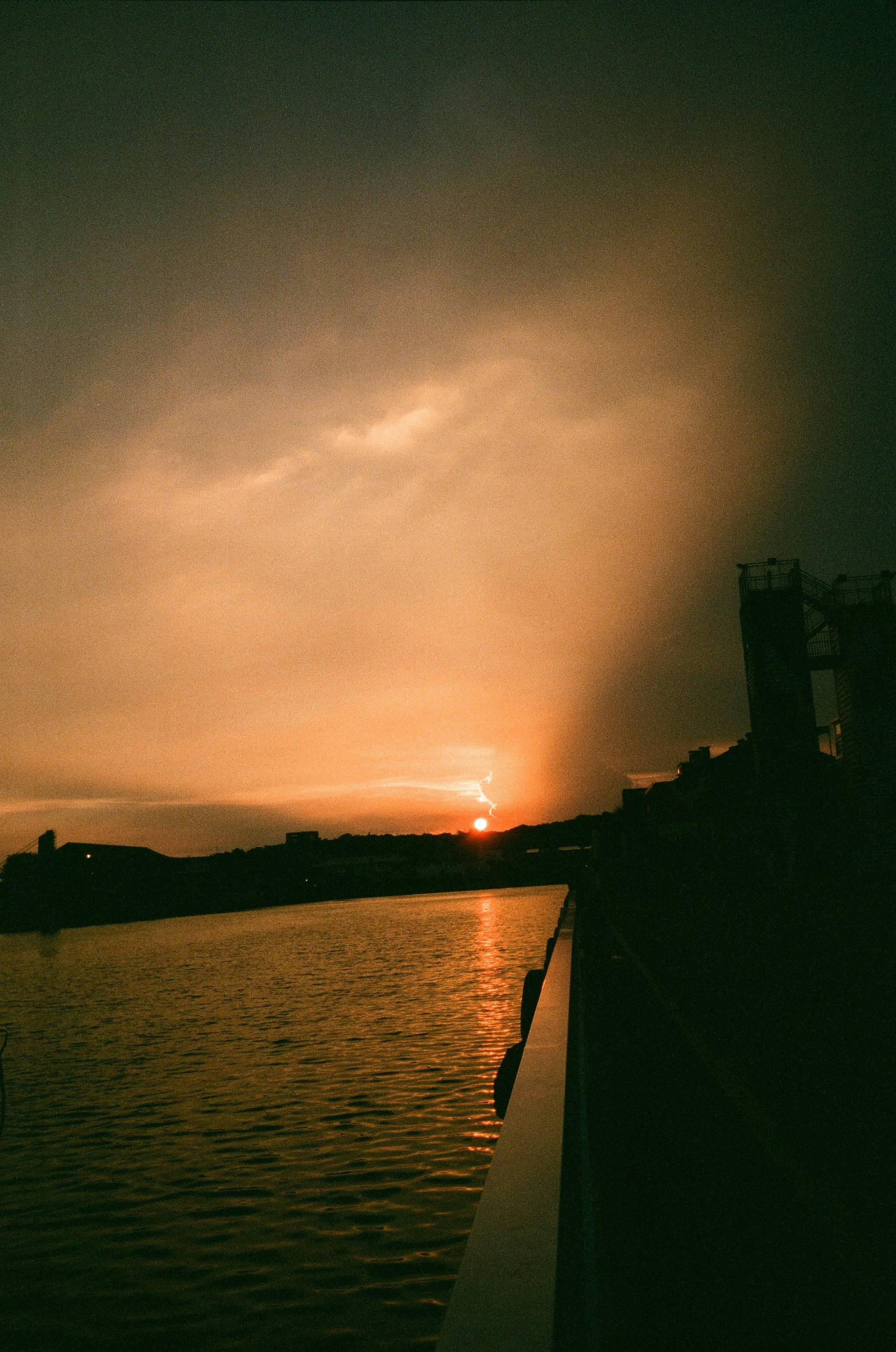 川沿いの堤防から見た夕焼け空と雲の光