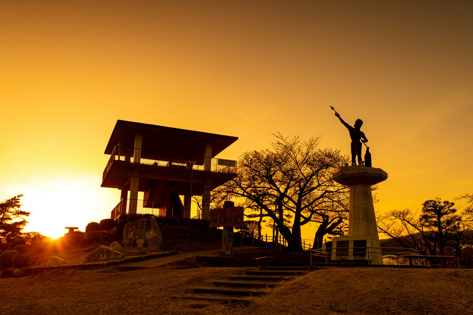 Silhouette of a statue and observation tower at sunset