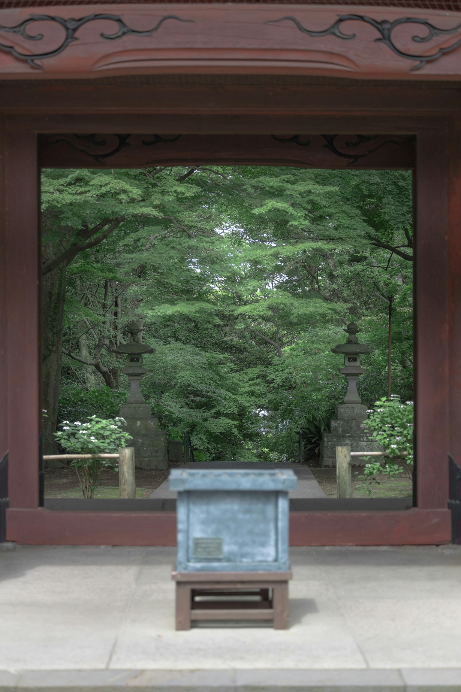 Wooden gate with a stone box in front of a lush garden