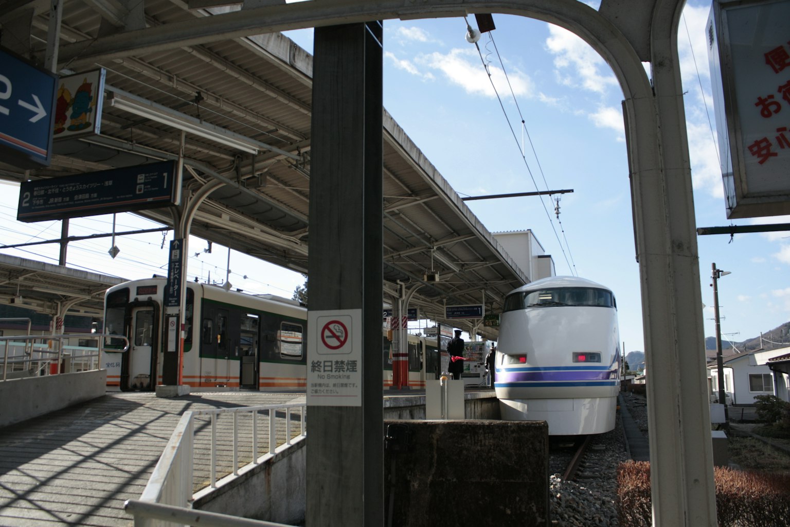 ชานชาลาสถานีรถไฟที่มีรถไฟจอดอยู่และท้องฟ้าสีฟ้า