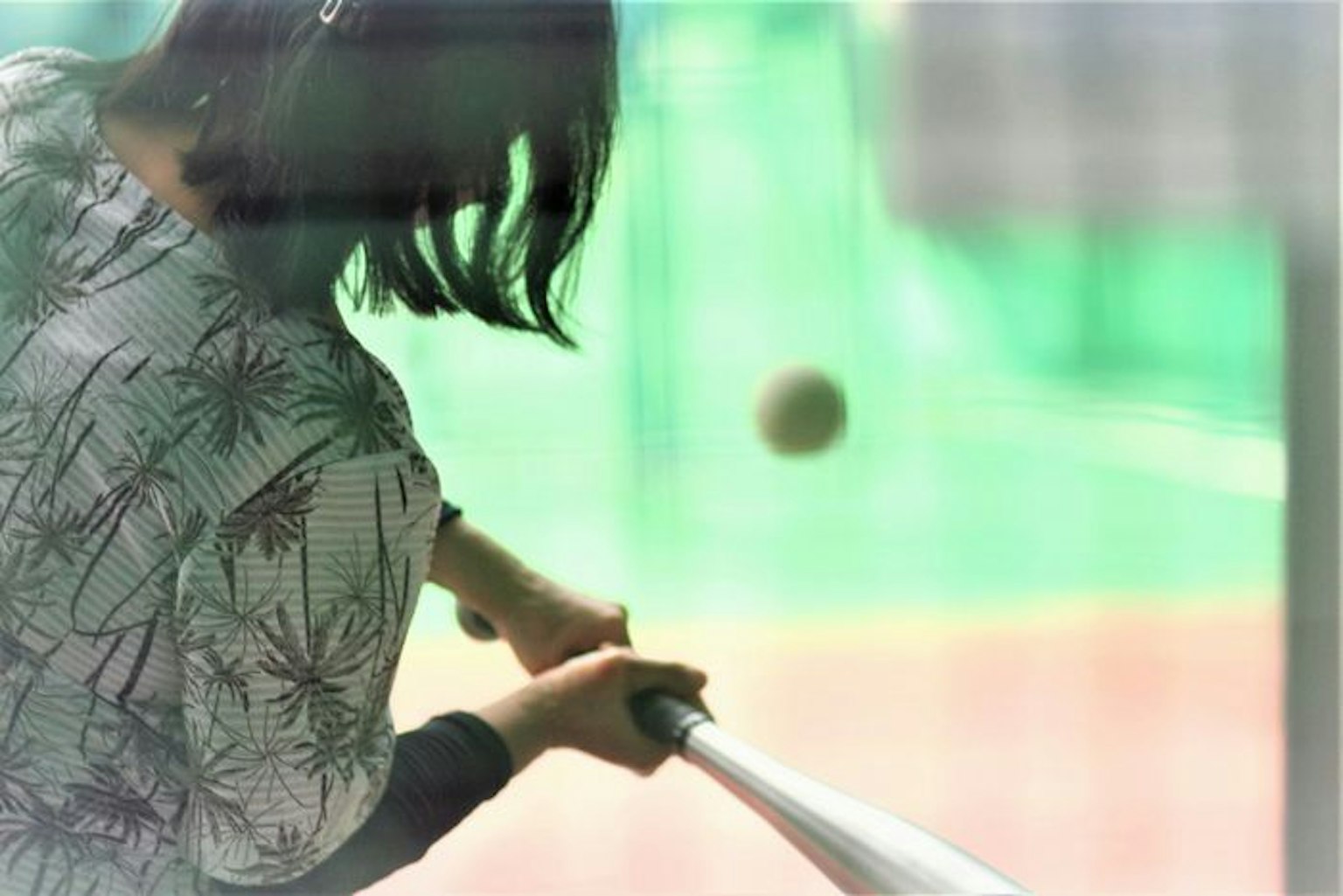 Donna che si esercita nel battuta con una mazza da baseball palla in movimento