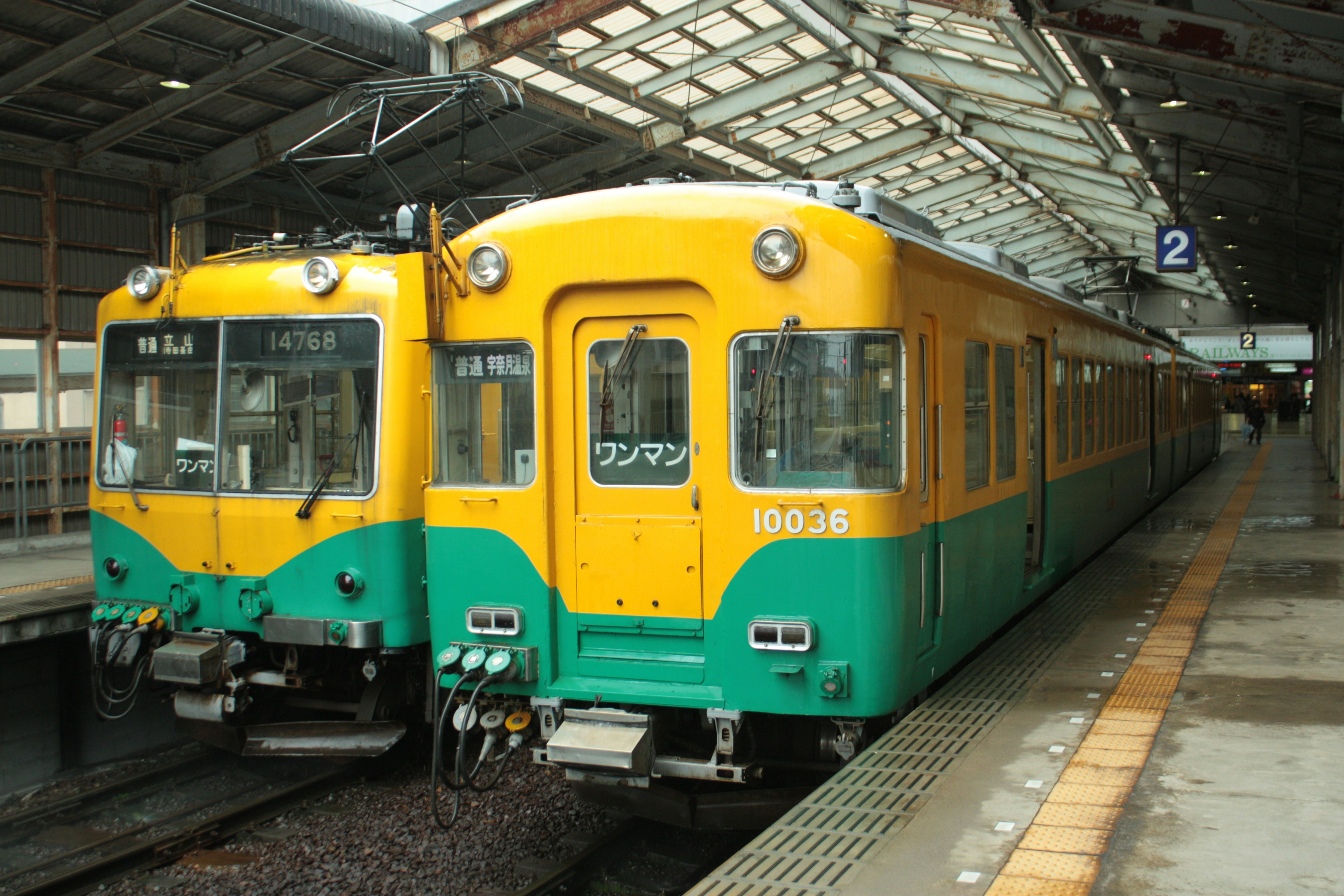 黄色と緑の電車が駅のホームに停車している