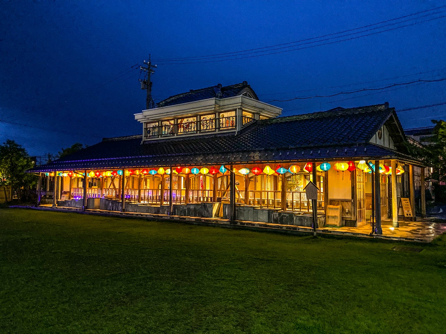 Exterior de una casa japonesa tradicional bajo el cielo nocturno linternas coloridas adornan el jardín