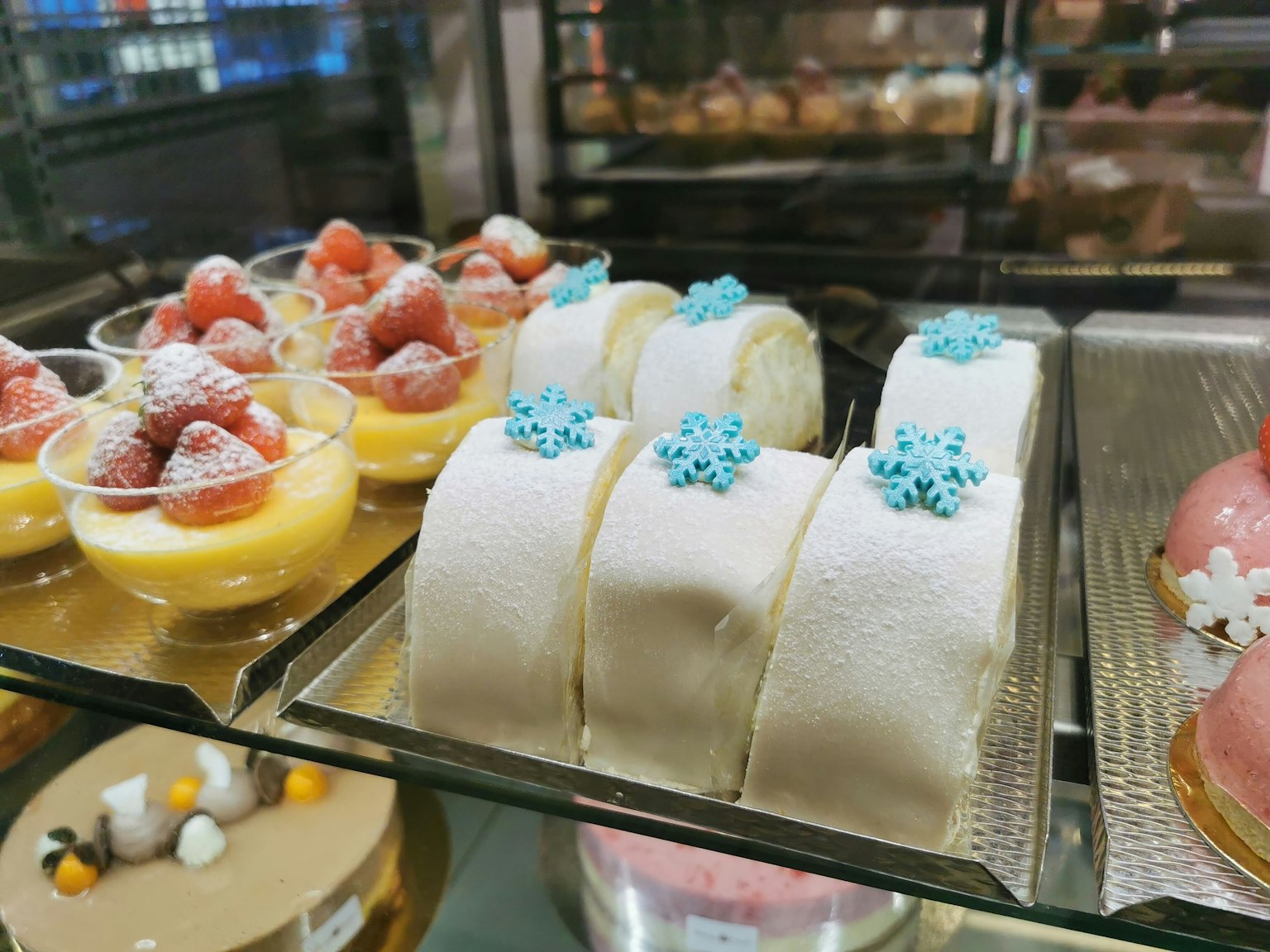 ตู้โชว์ขนมหวานหลากสีที่มีขนมครีมสตรอว์เบอรีและขนมตกแต่งด้วยสีฟ้า