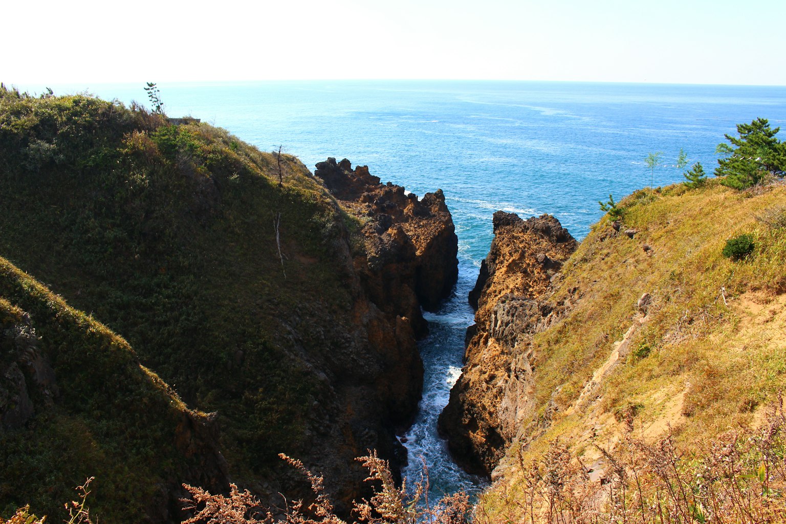 Schmaler Canyon zwischen felsigen Klippen und blauem Ozean