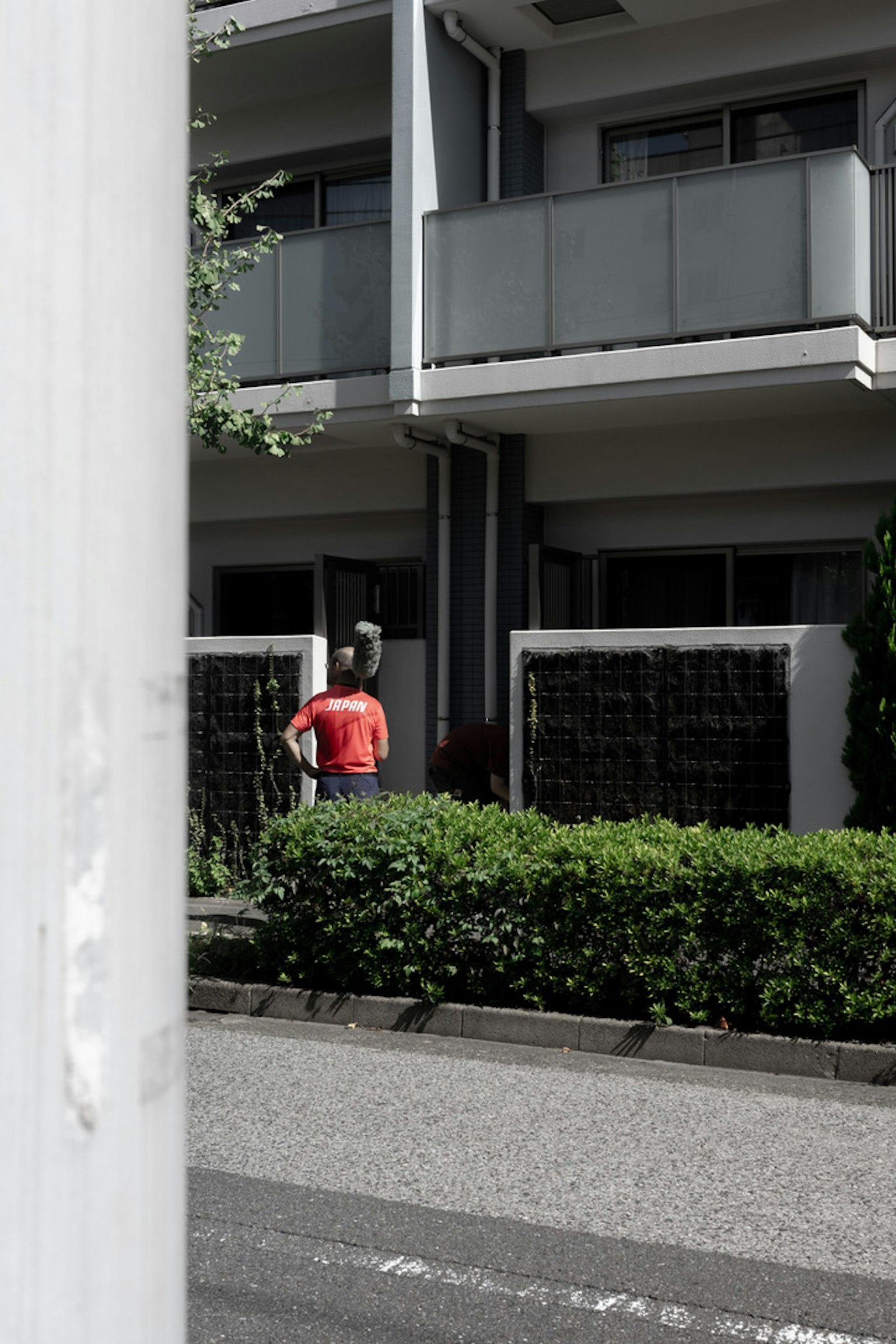 Person in rotem Shirt steht vor einem Wohngebäude