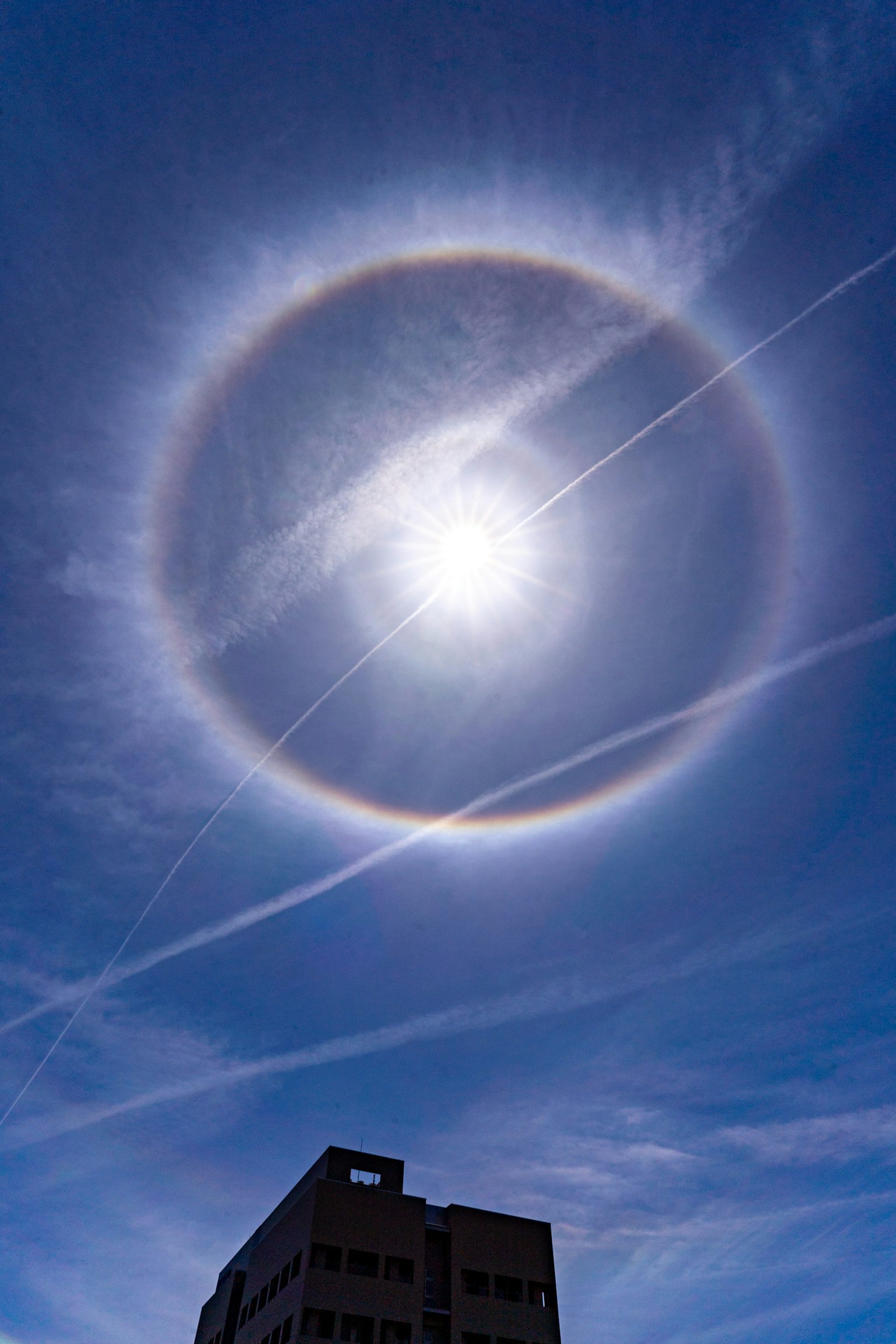 Cincin pelangi besar di sekitar matahari di langit biru