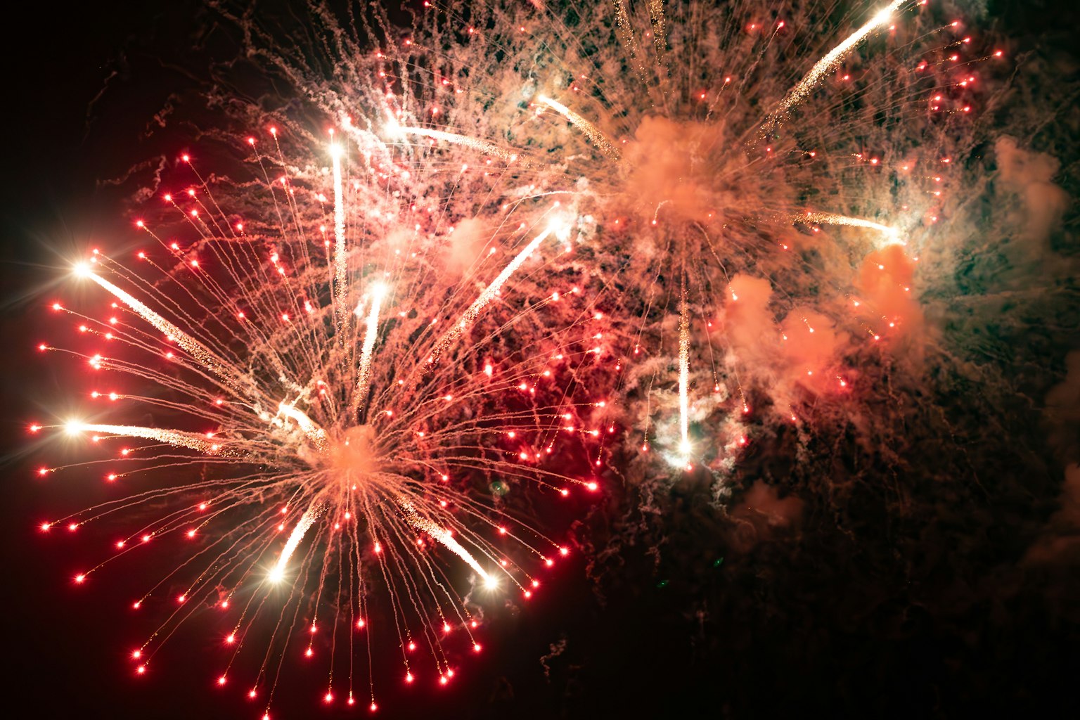 Fuochi d'artificio rossi e bianchi brillanti che esplodono nel cielo notturno