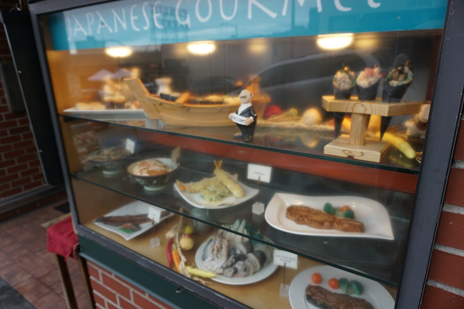 Vitrine présentant une cuisine japonaise avec sushi sashimi tempura et divers plats magnifiquement présentés