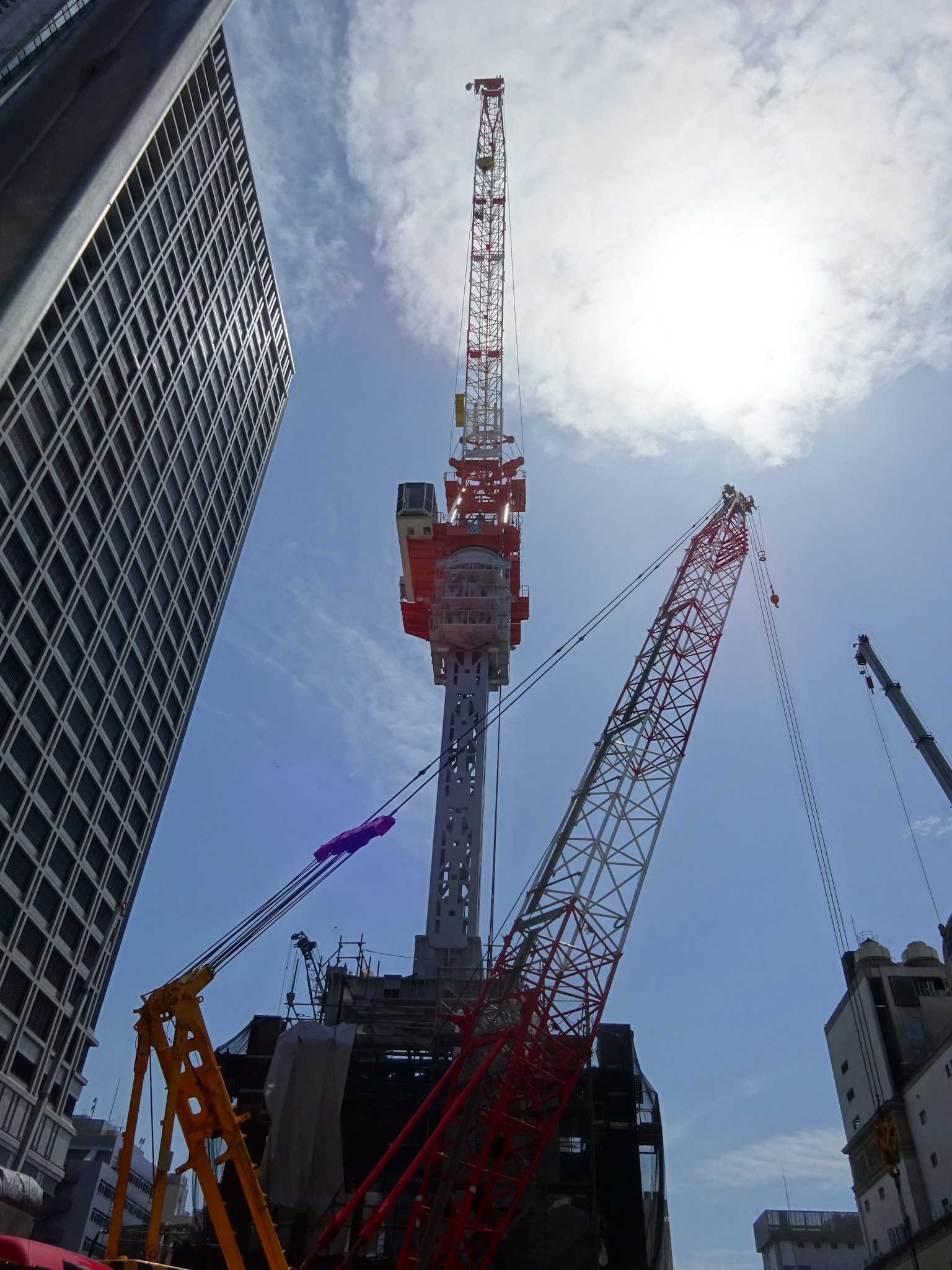 Situs konstruksi dengan crane di bawah langit biru dan matahari