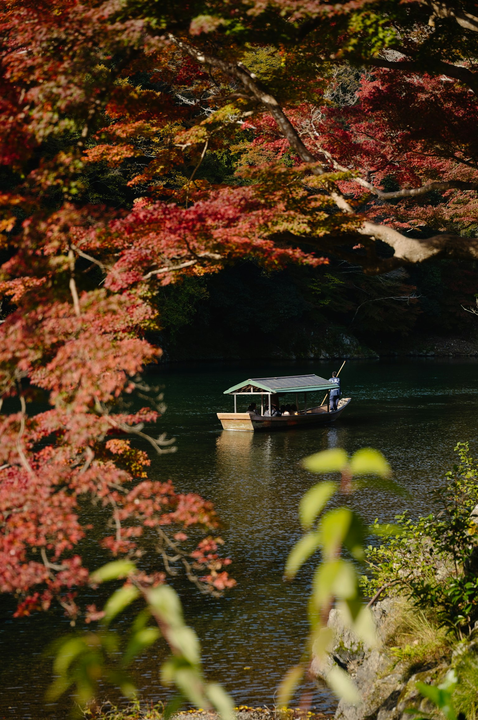 秋の紅葉に囲まれた静かな川に浮かぶ小舟