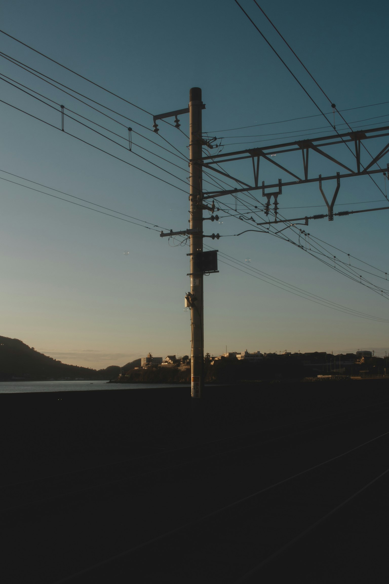 Silhouette d'un poteau de chemin de fer et de fils aériens au crépuscule