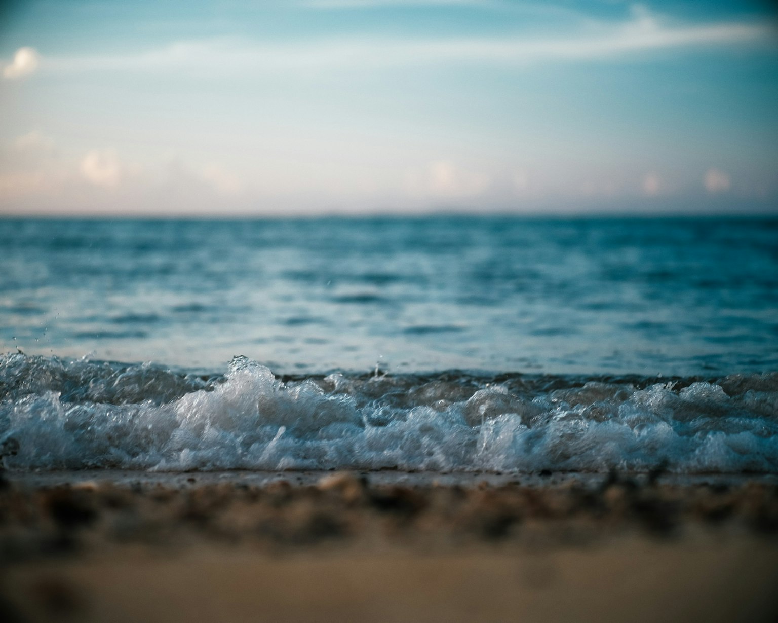 海浪輕輕拍打在沙灘上，藍天映襯