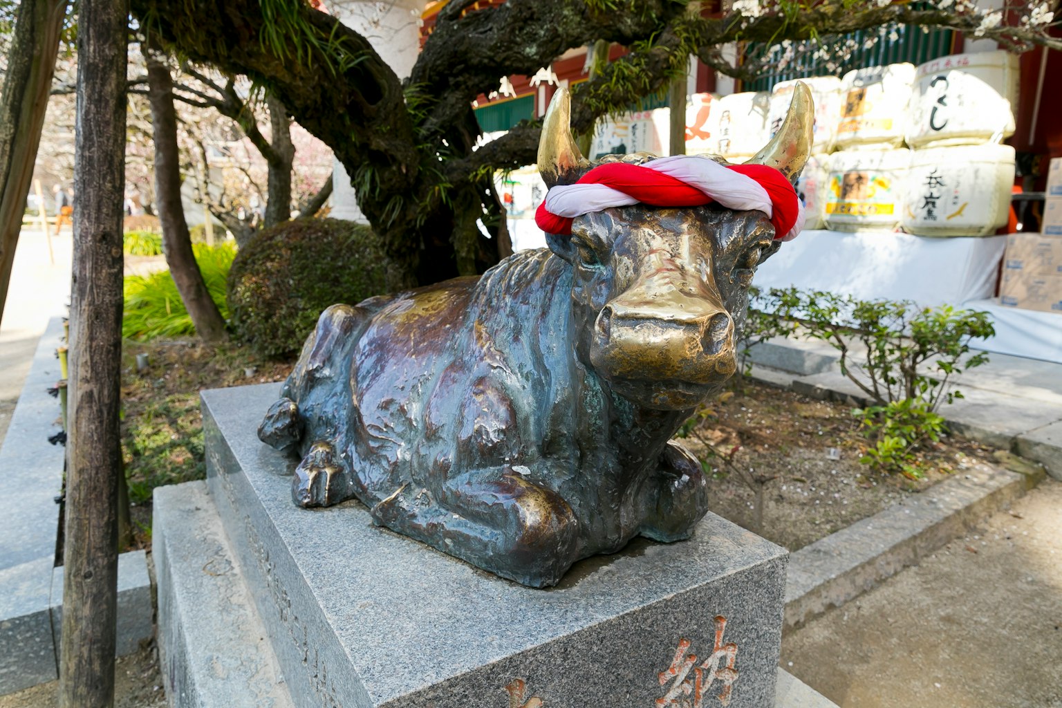 Patung perunggu sapi dengan topi merah di lingkungan kuil
