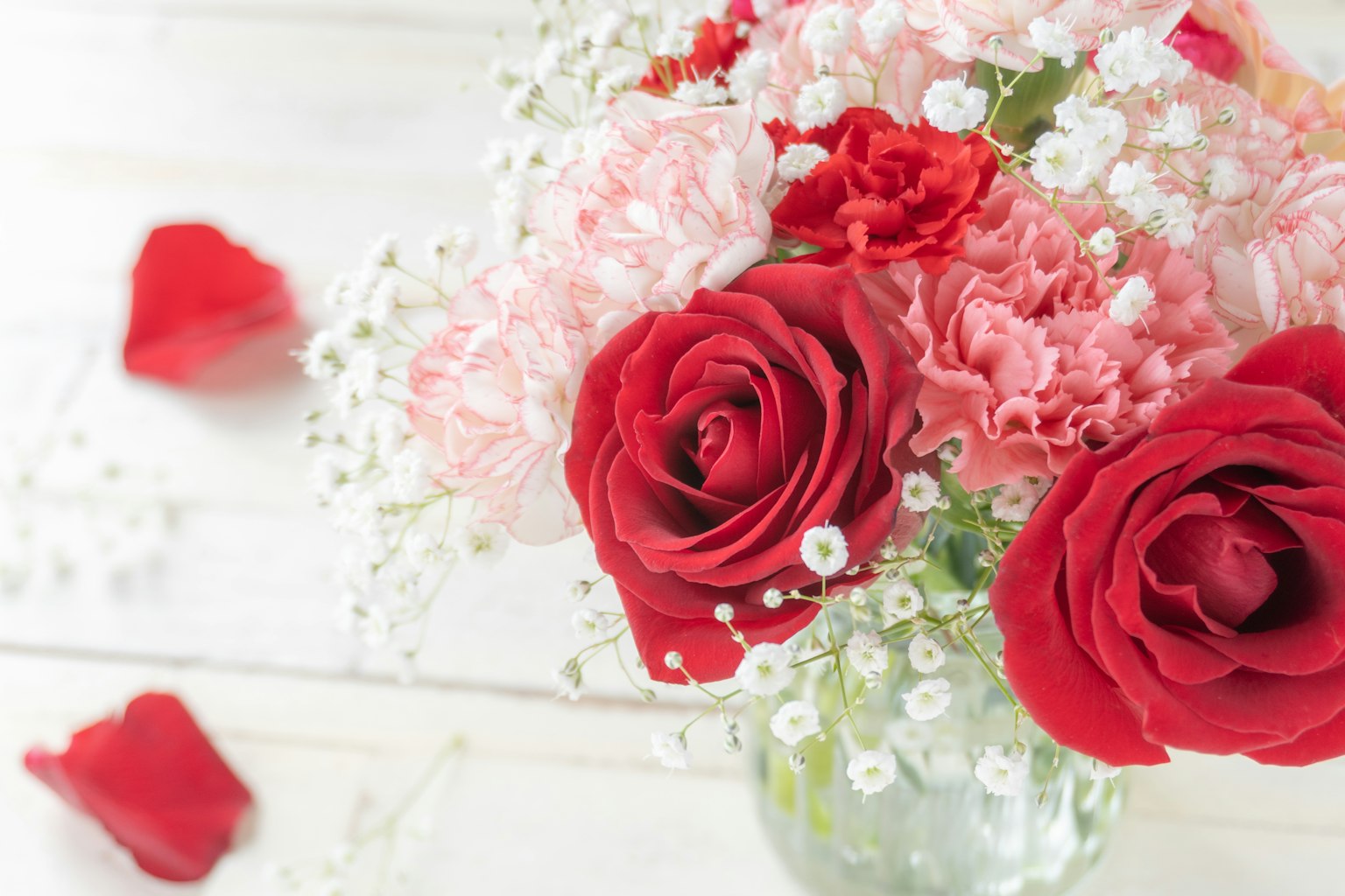 Strauß aus roten Rosen und Nelken mit Schleierkraut und roten Rosenblättern