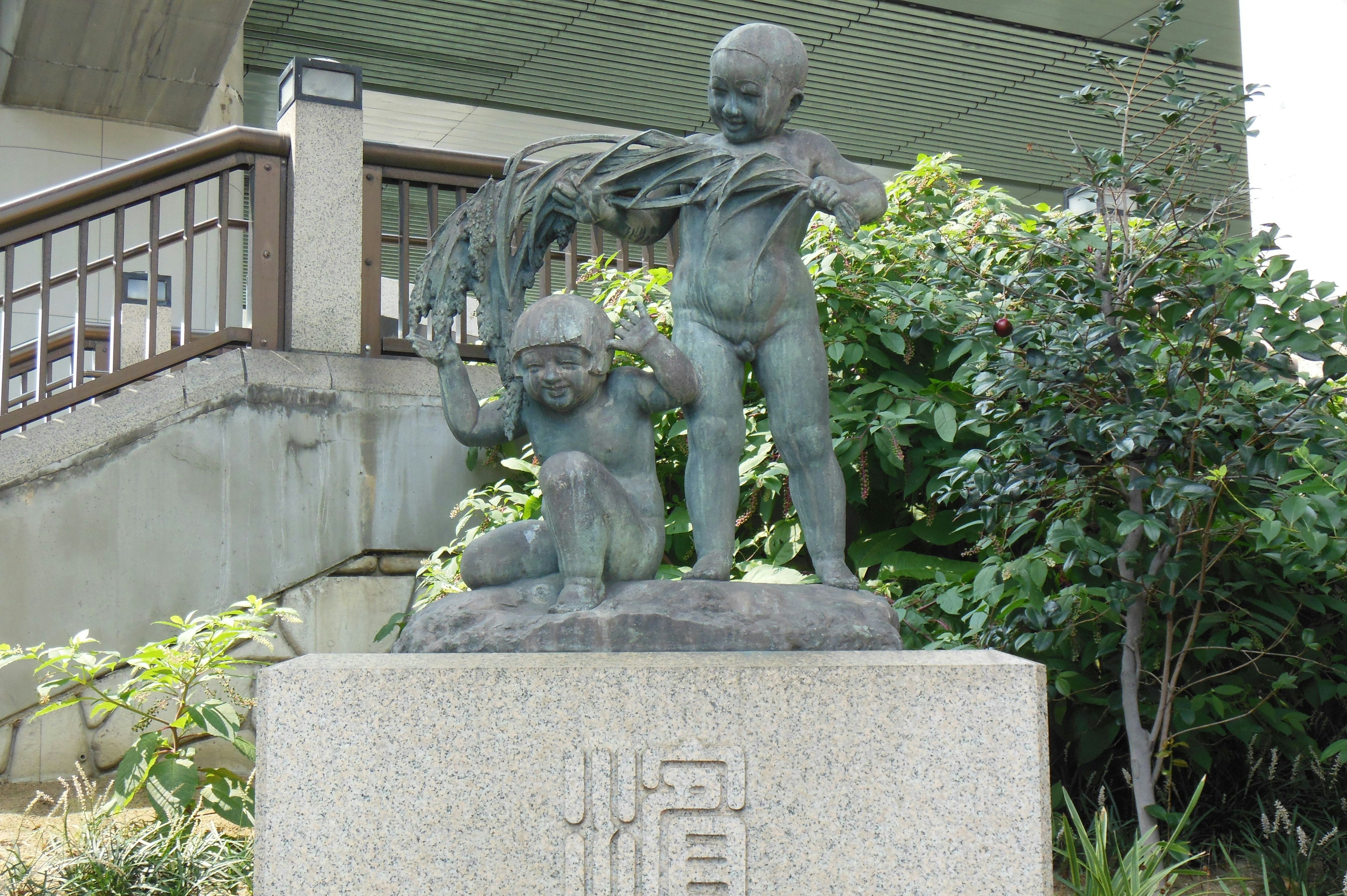 庭園の台座に置かれた銅像と子どもの像
