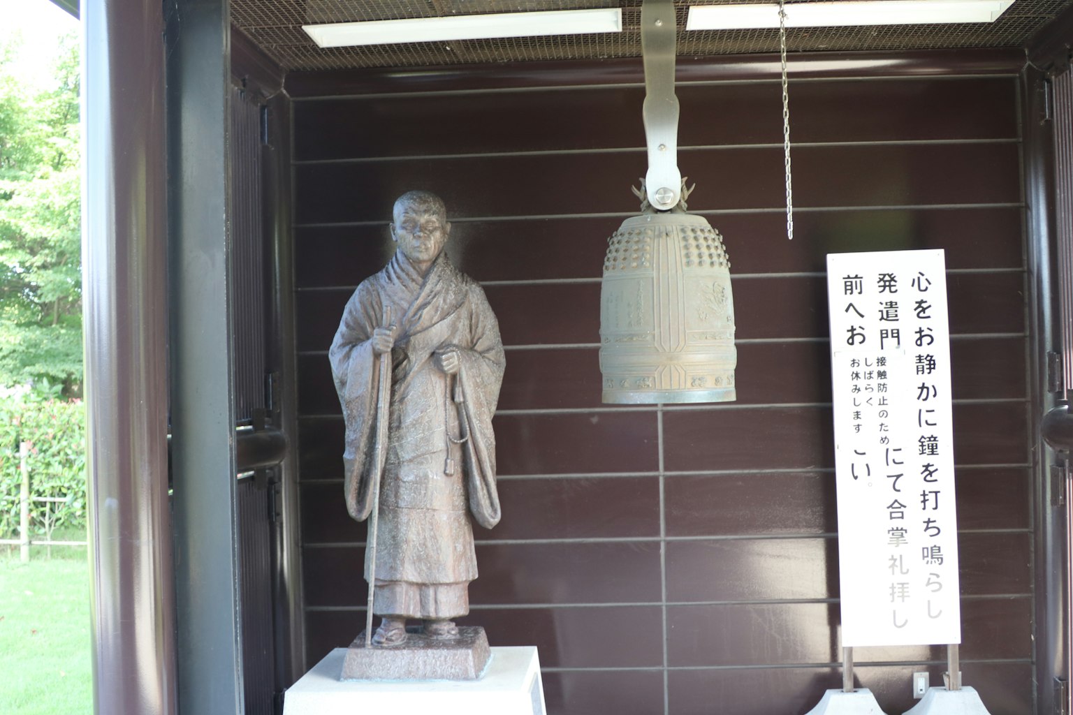Interno di una struttura moderna con una statua e una campana