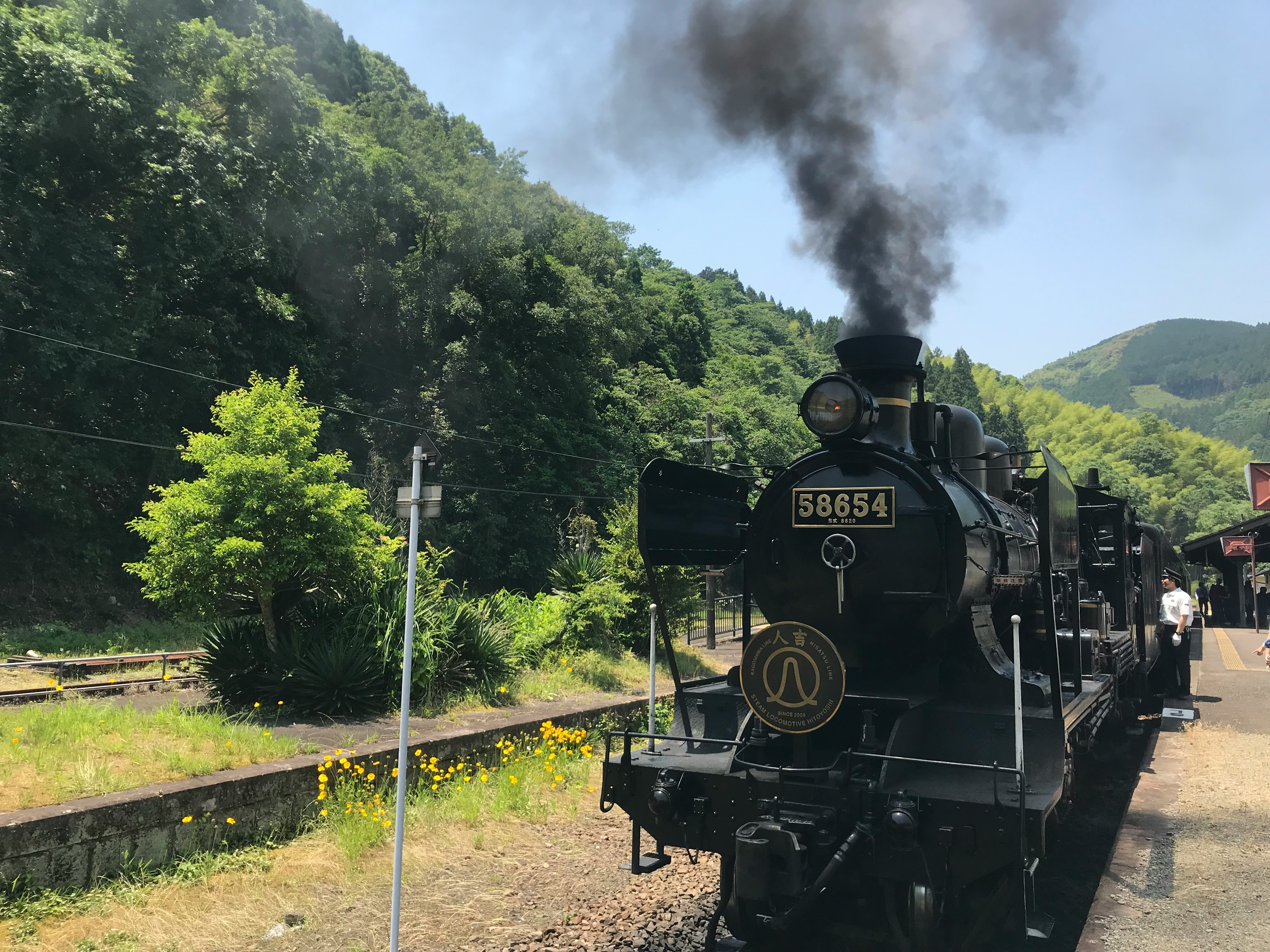 山あいの線路を走る蒸気機関車のある風景