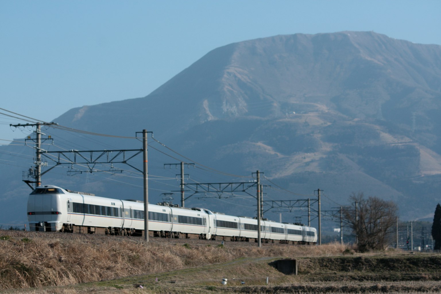 Ein weißer Schnellzug fährt mit einer Bergkulisse