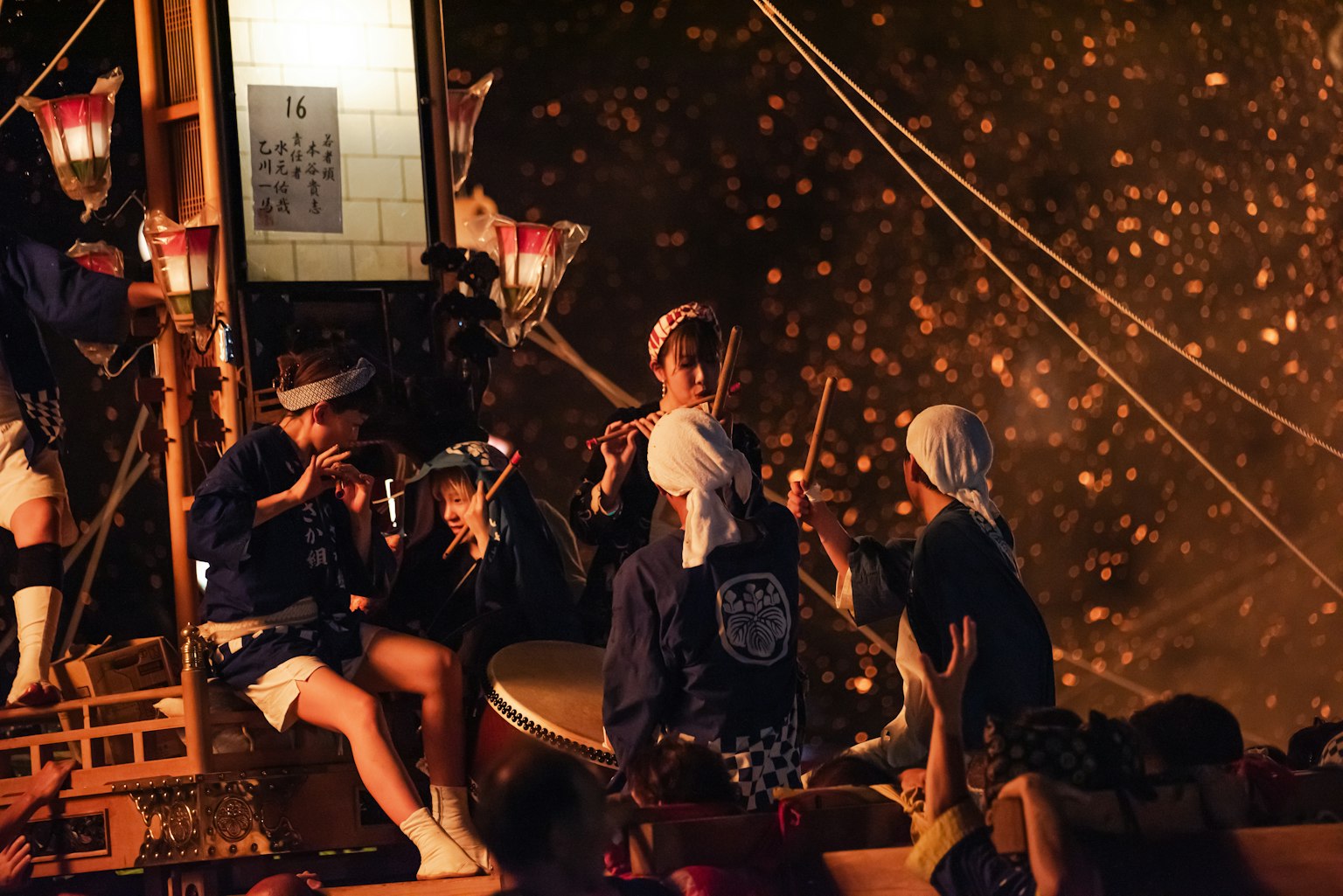 People preparing for a festival with sparkling fireworks in the background