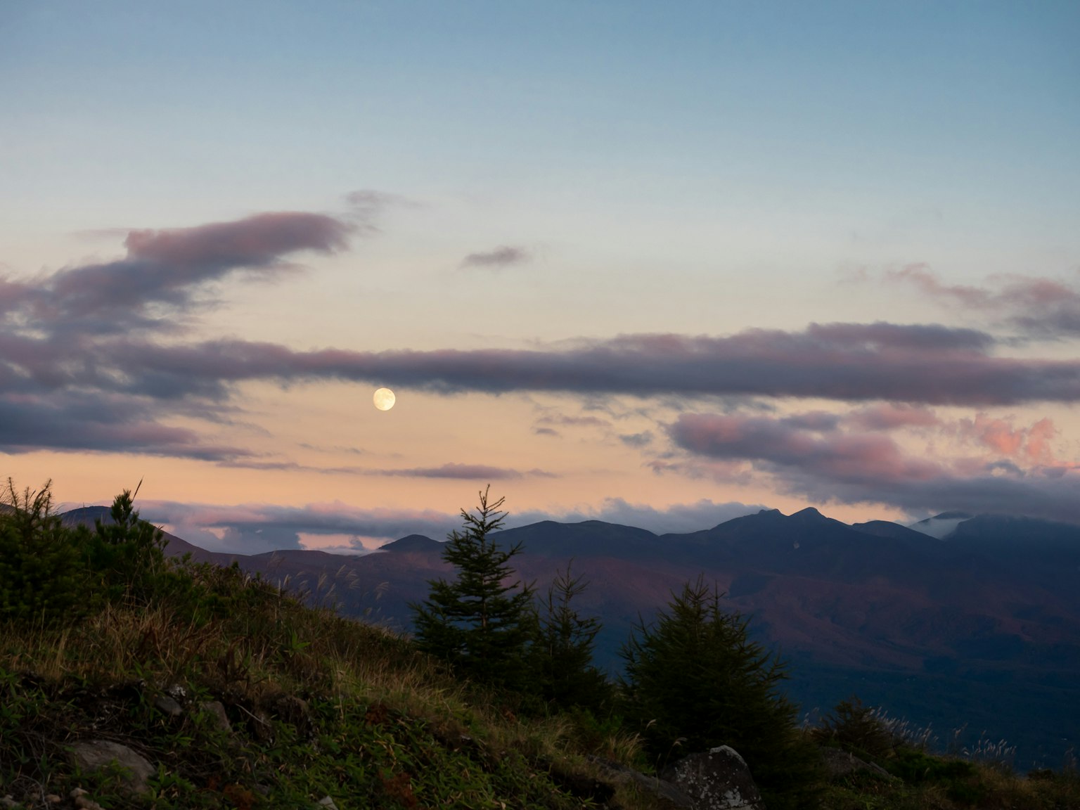 Scenic view of mountains with a moon in the twilight sky