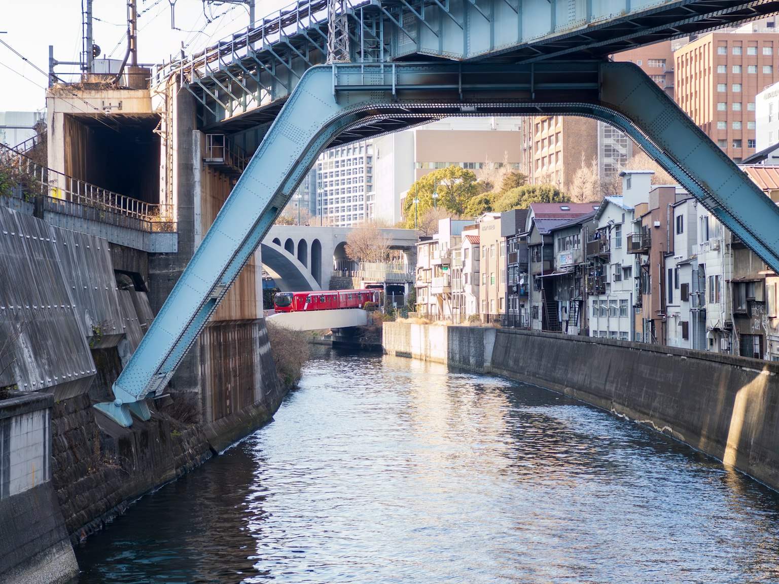 一座蓝色桥梁横跨河流，周围有建筑物