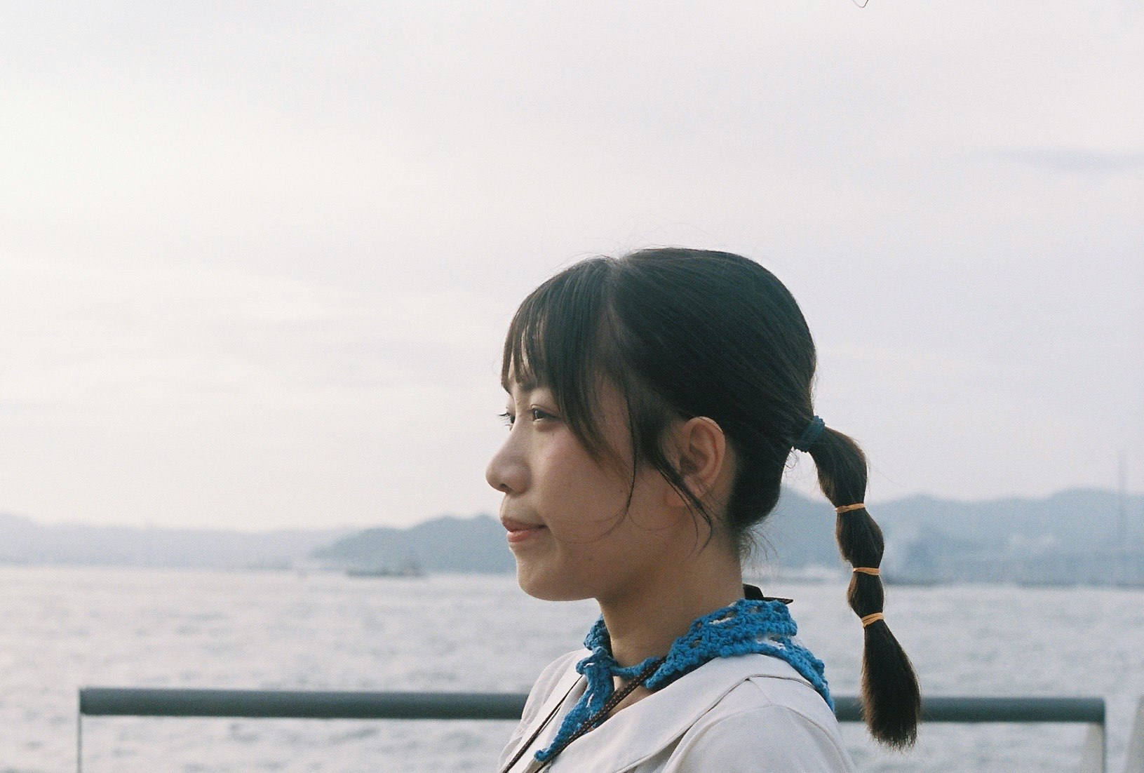 海辺のベンチに座る横顔の女性