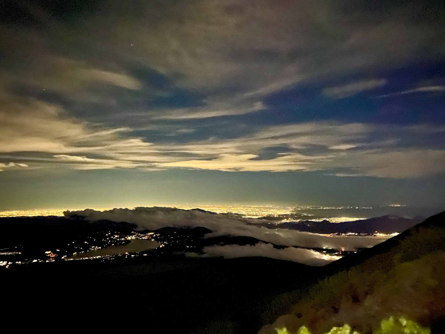 夜空中雲彩和山脈及遠處燈光的風景