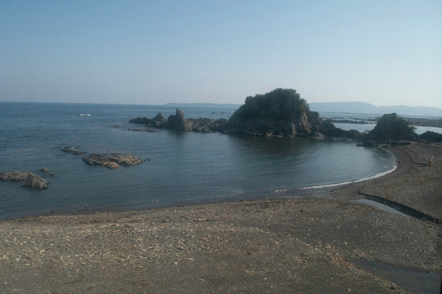 海岸风景，包括宁静水面、岩石岛屿、宁静天空和沙滩
