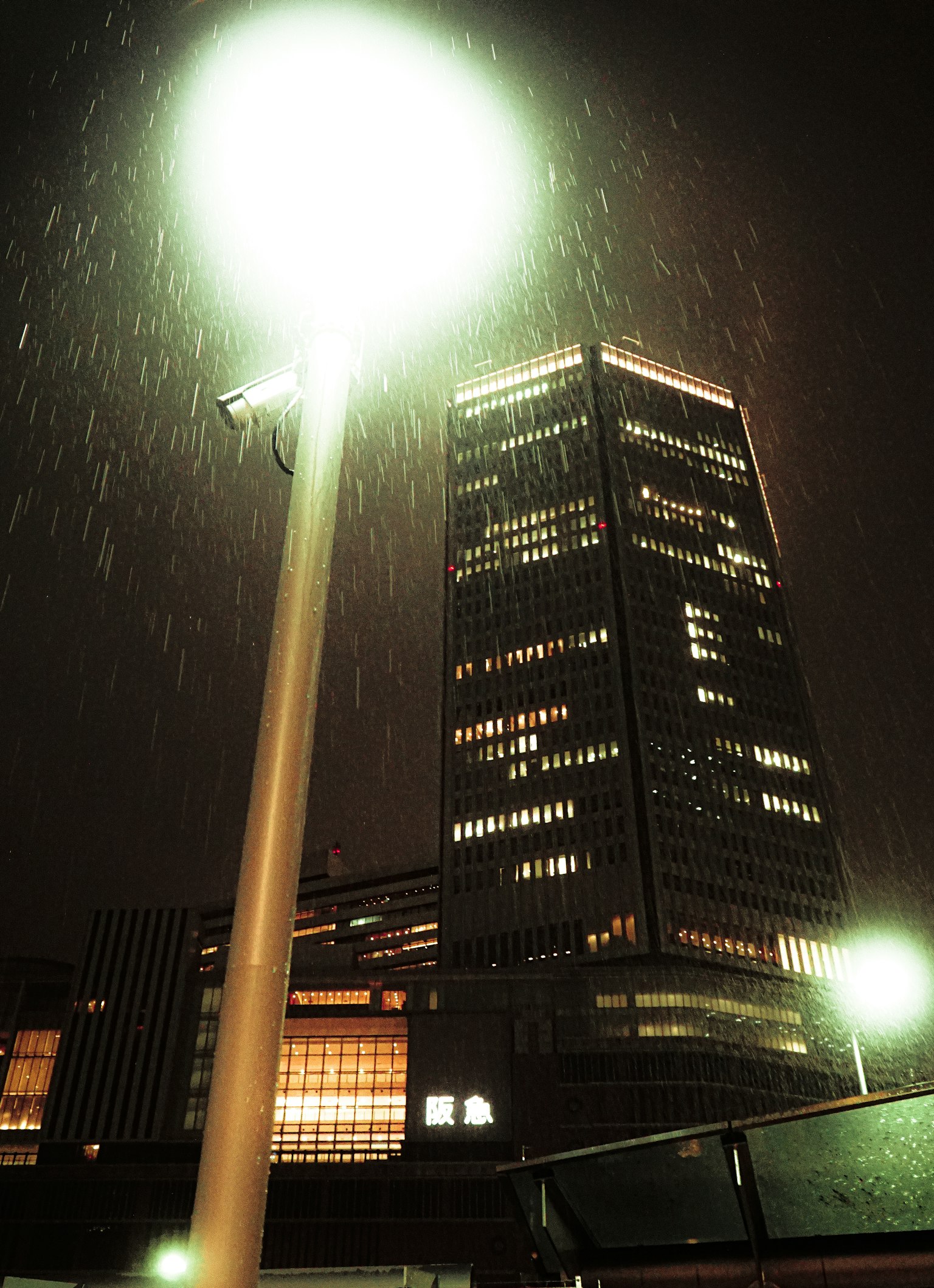 Scène urbaine avec un bâtiment élevé illuminé la nuit et un lampadaire